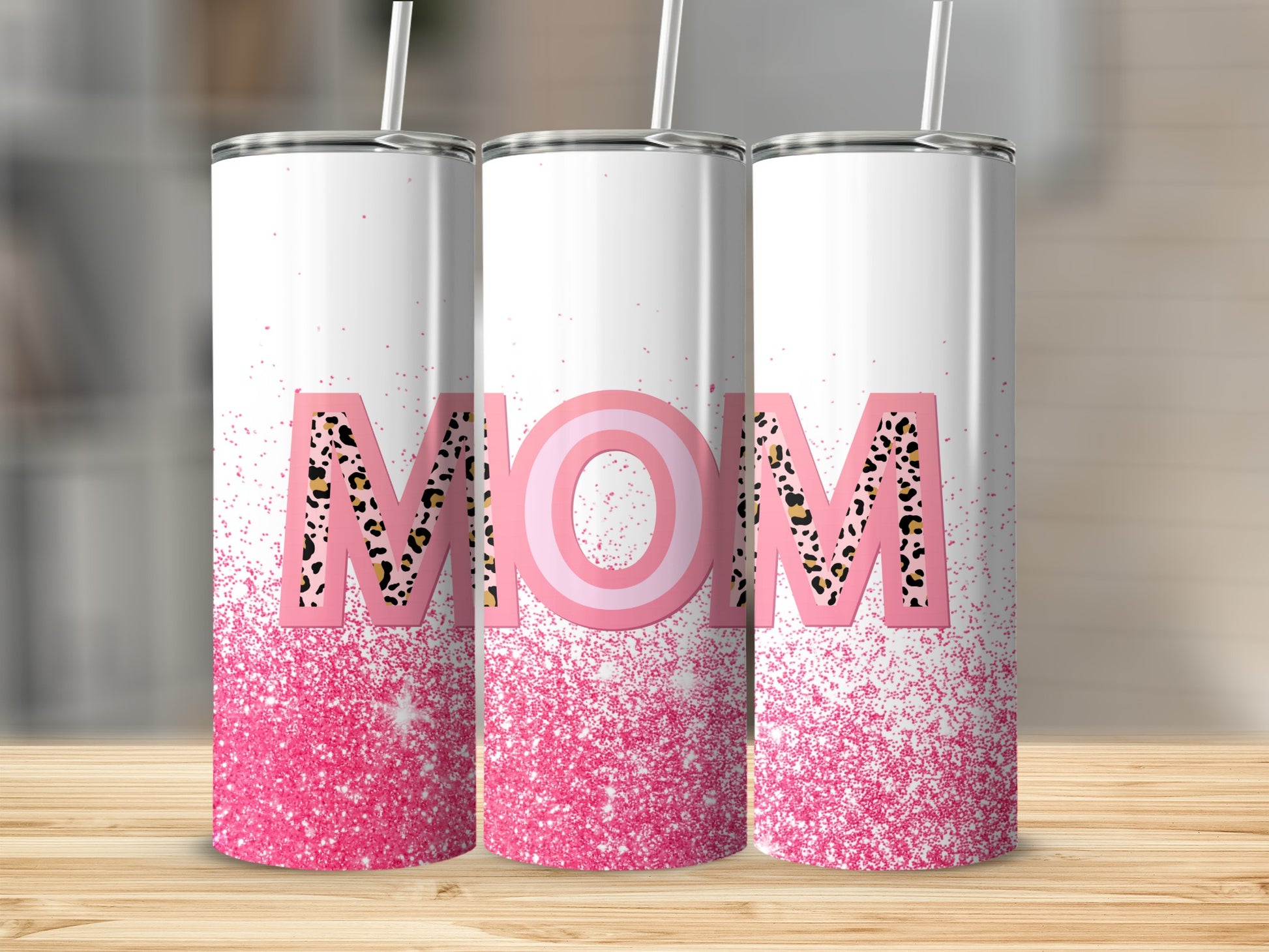 Pink glitter tumbler with "MOM" in leopard print, standing on a wooden surface.