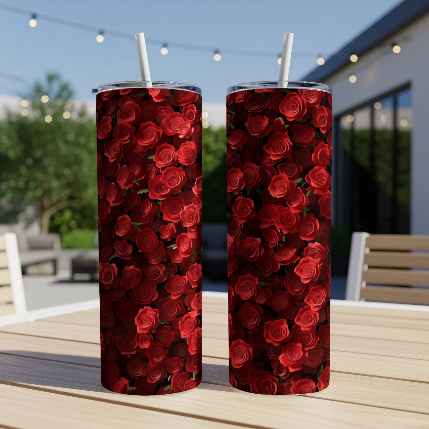 Two tumblers with a red rose floral pattern on an outdoor table.
