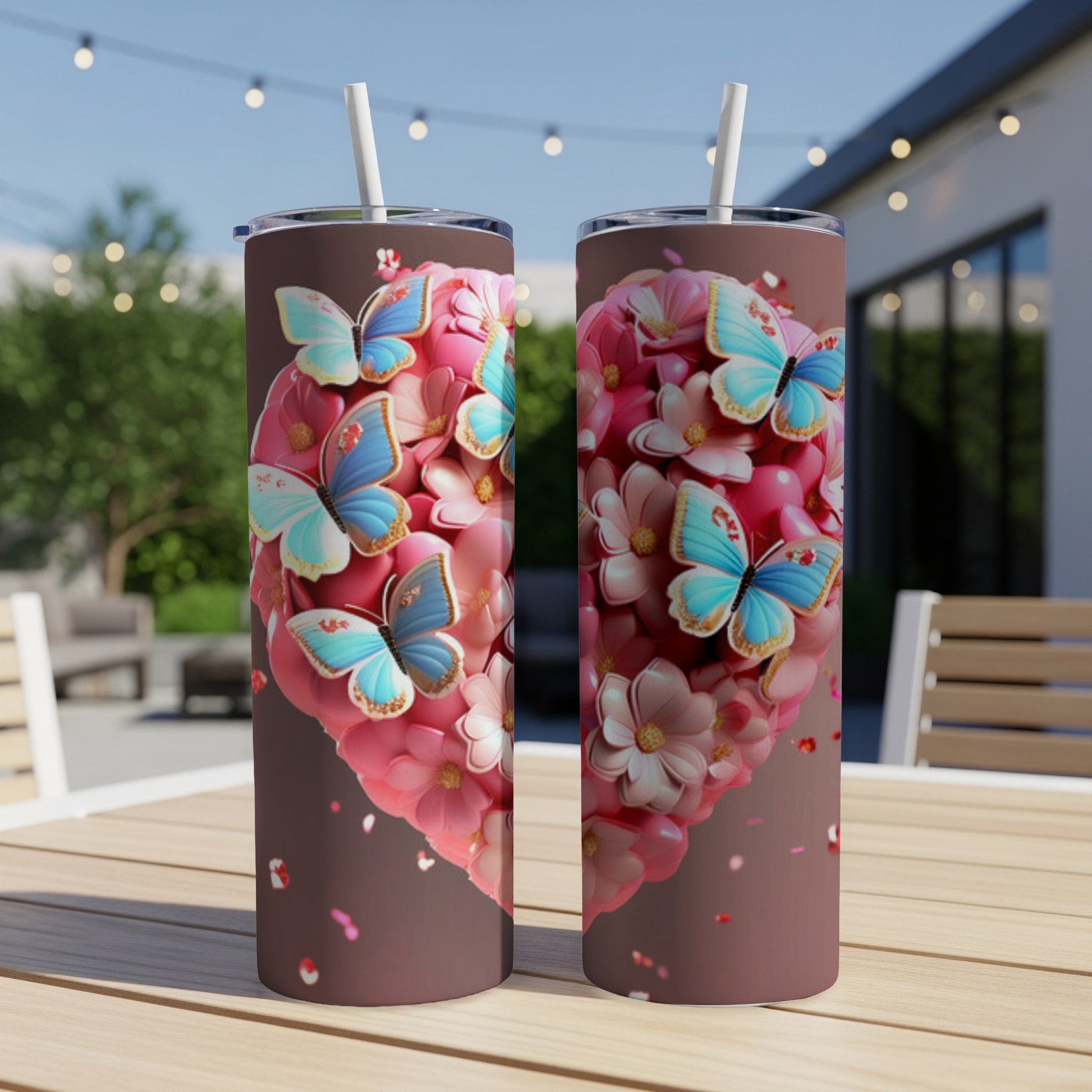 Two heart-shaped tumblers with butterflies and flowers, outdoors on a table.