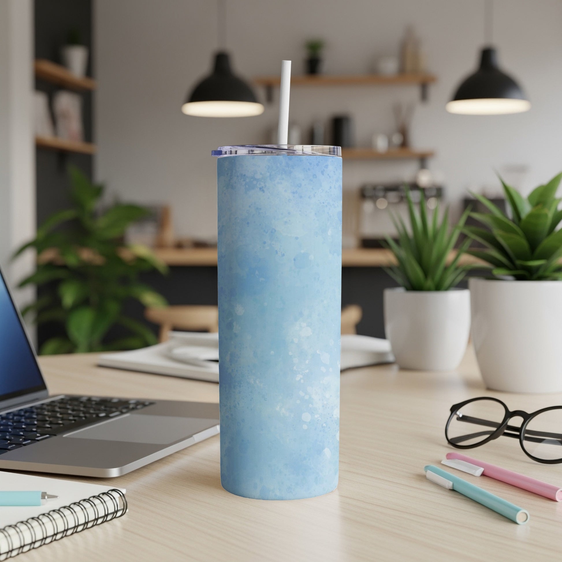Blue speckled tumbler with straw on a desk with a laptop.
