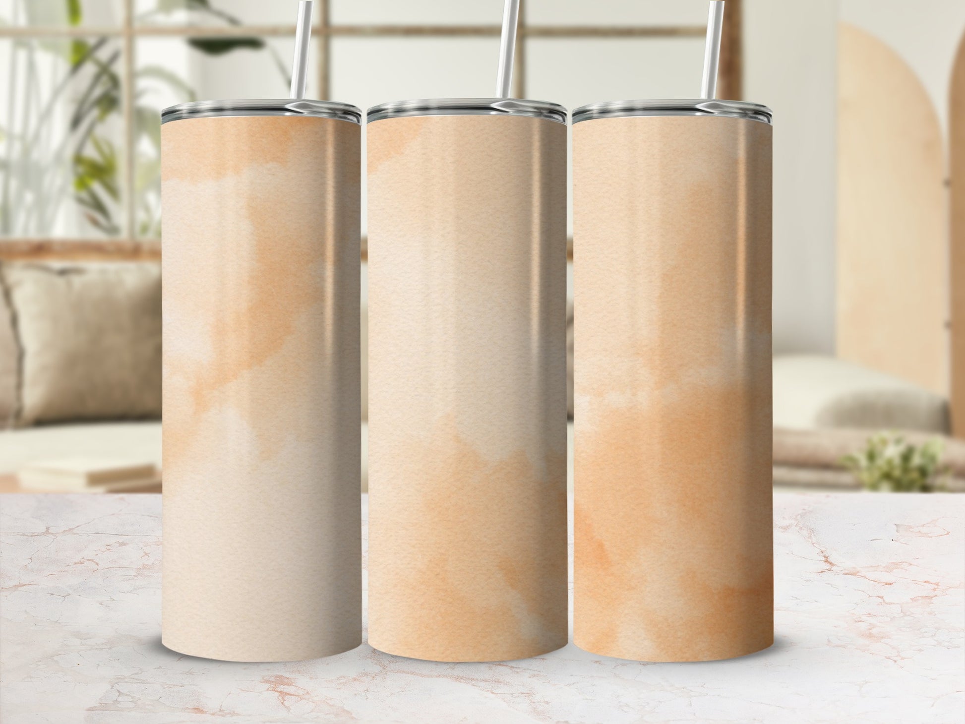 Three cream and peach watercolor tumblers with straws stand on a marbled surface.