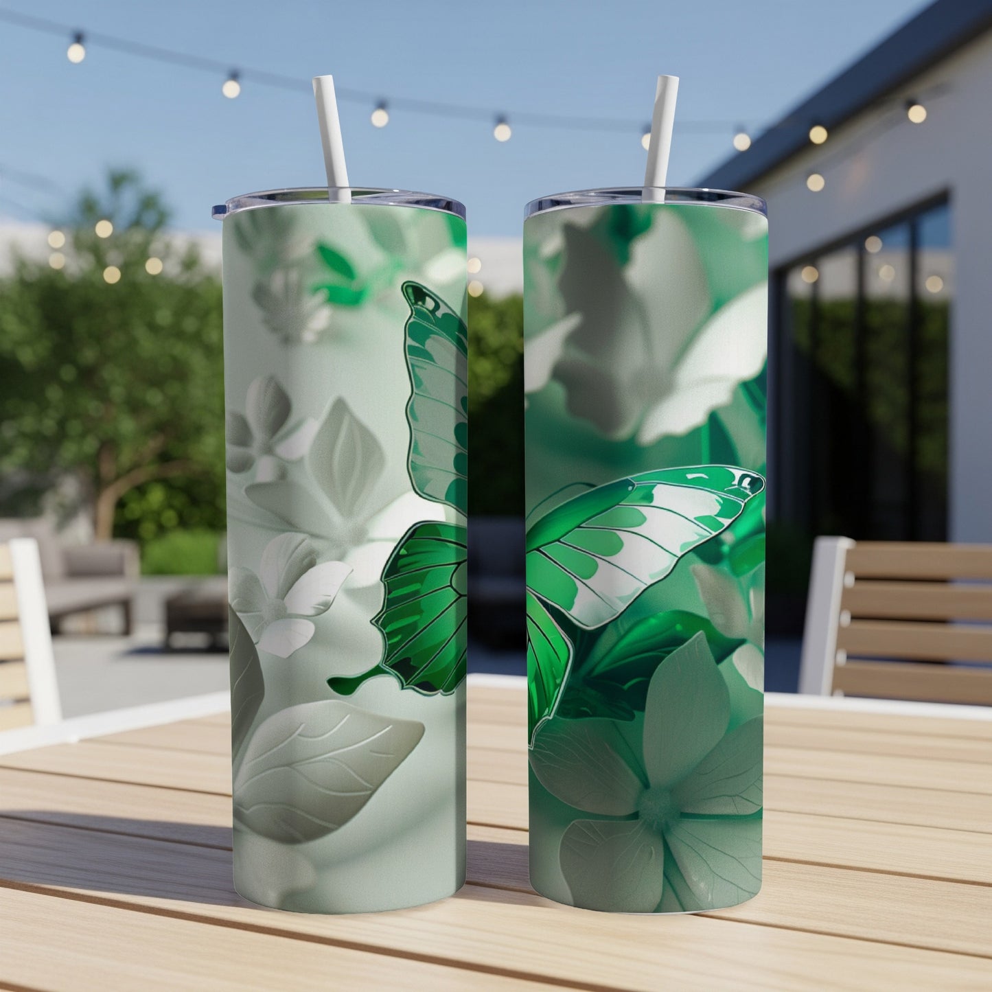 Two tall green tumblers with butterfly and floral designs sit on a table.