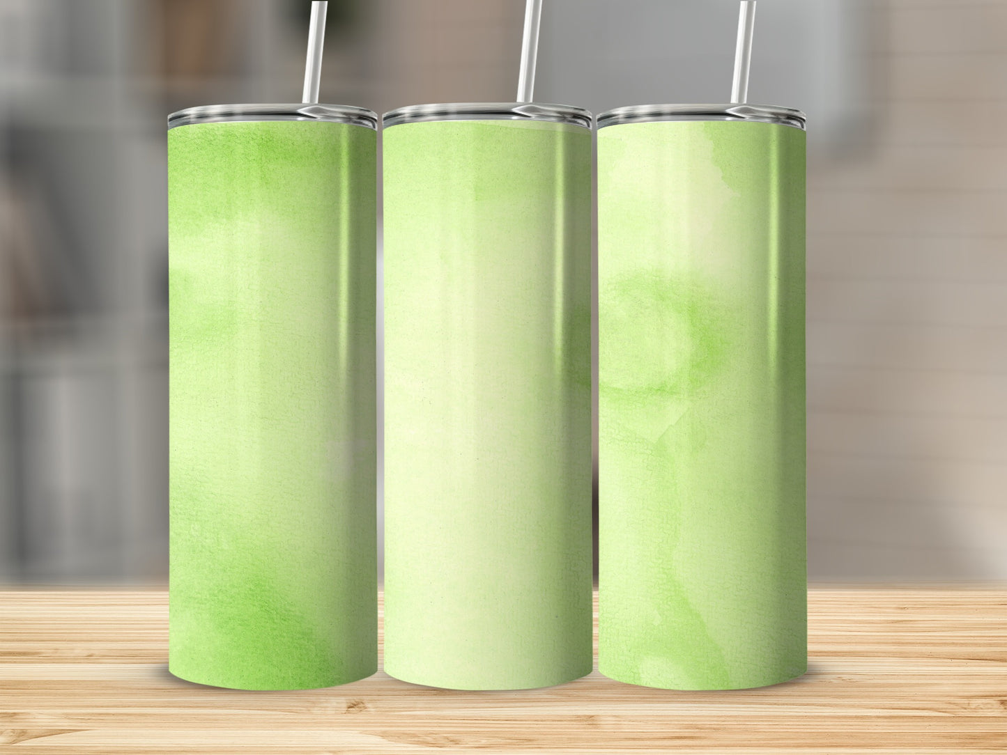 Three tumblers with a light green watercolor pattern stand on a wooden surface.
