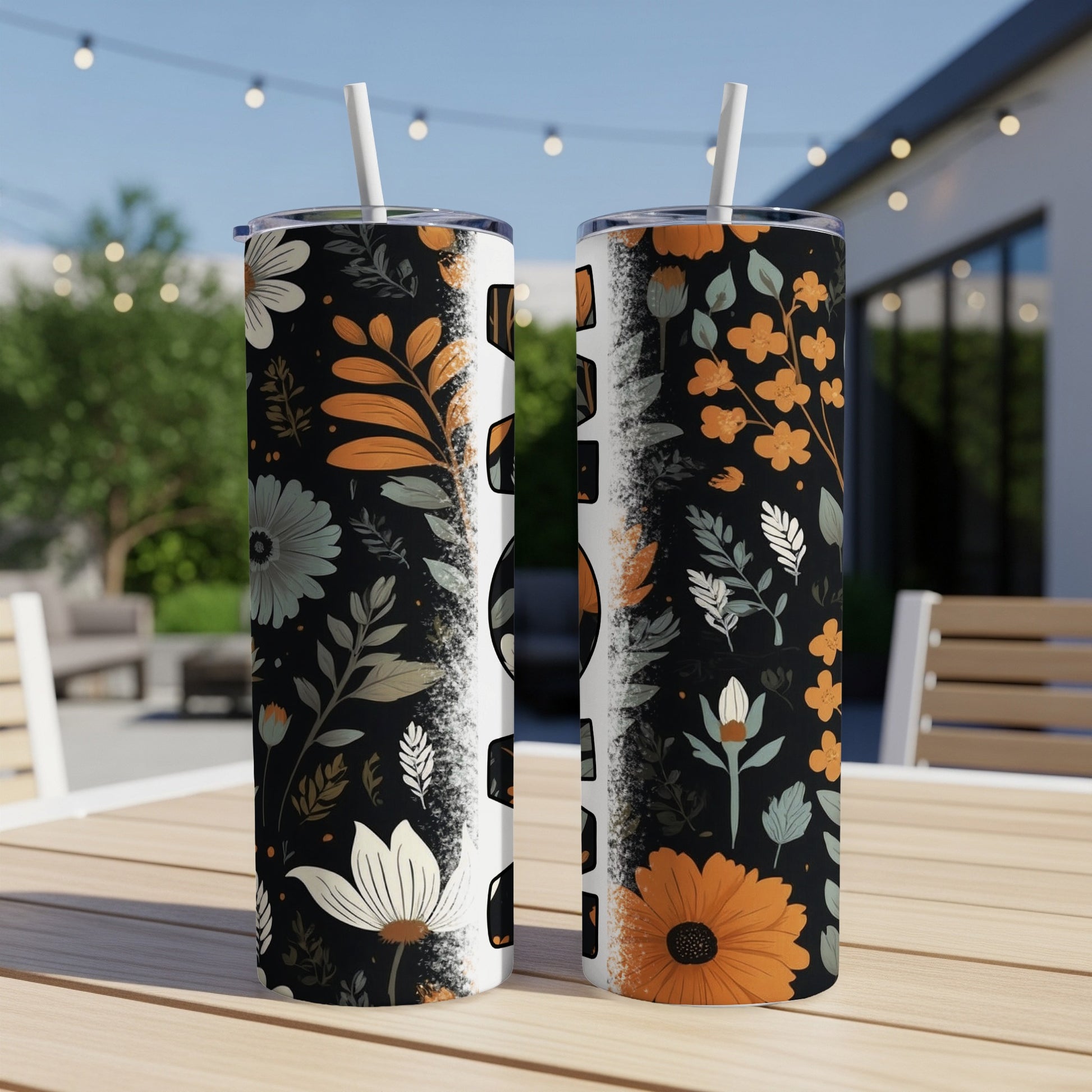 Two tumblers with a floral pattern and straw on a table.