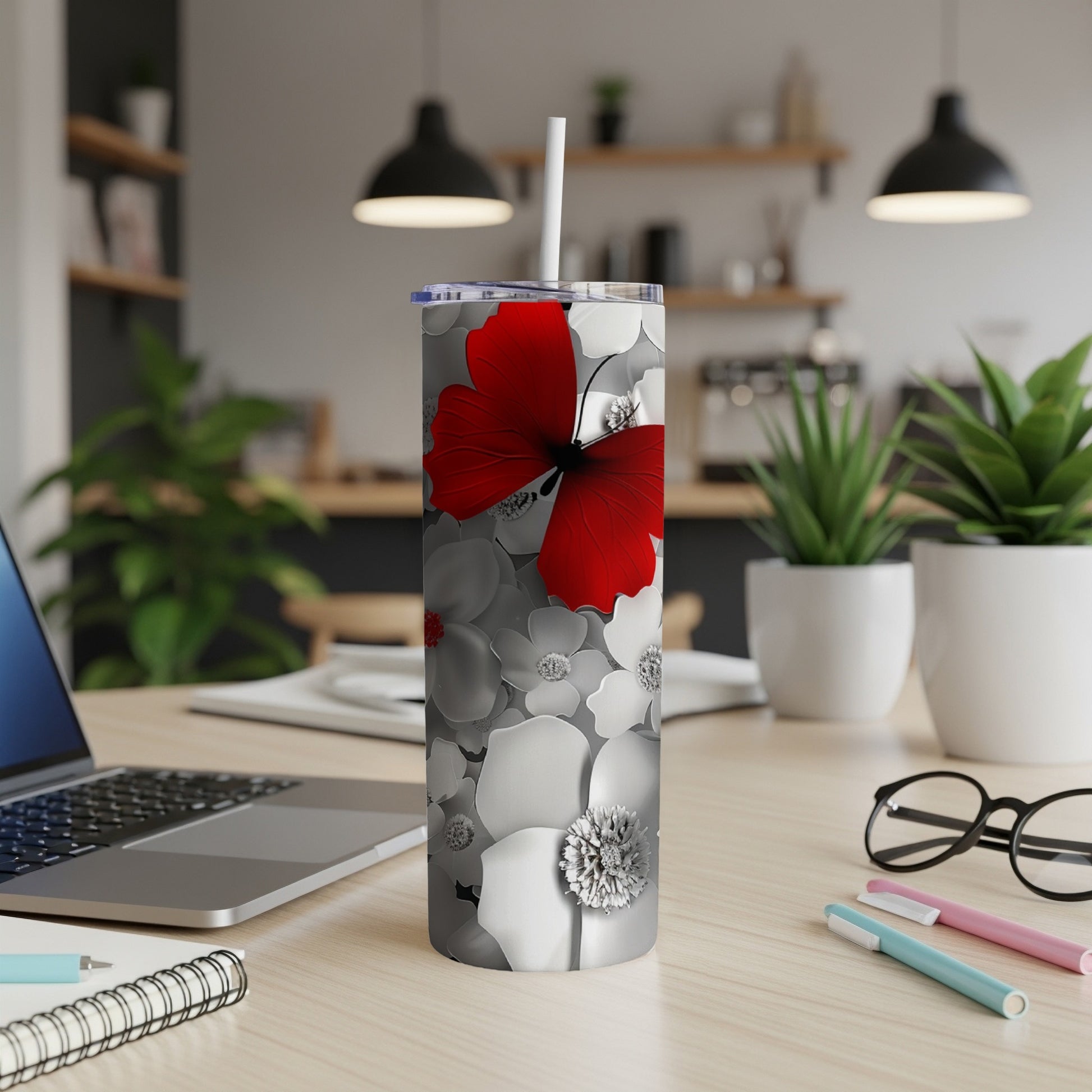 White tumbler with red butterfly and floral design on desk.