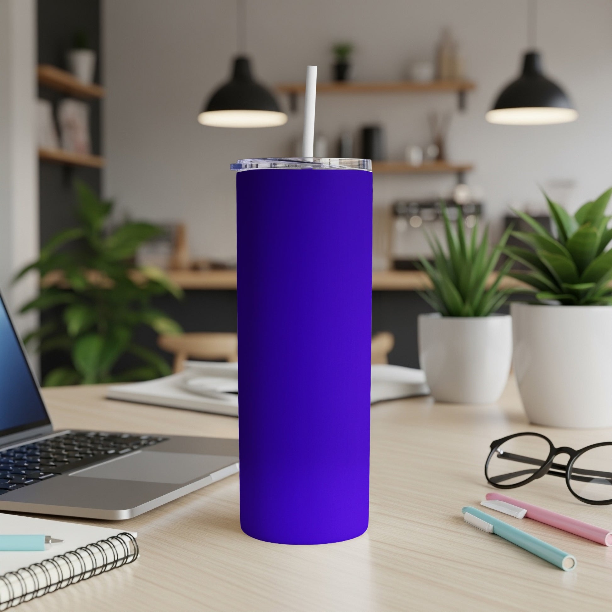 A vibrant purple tumbler with a white straw sits on a wooden desk.