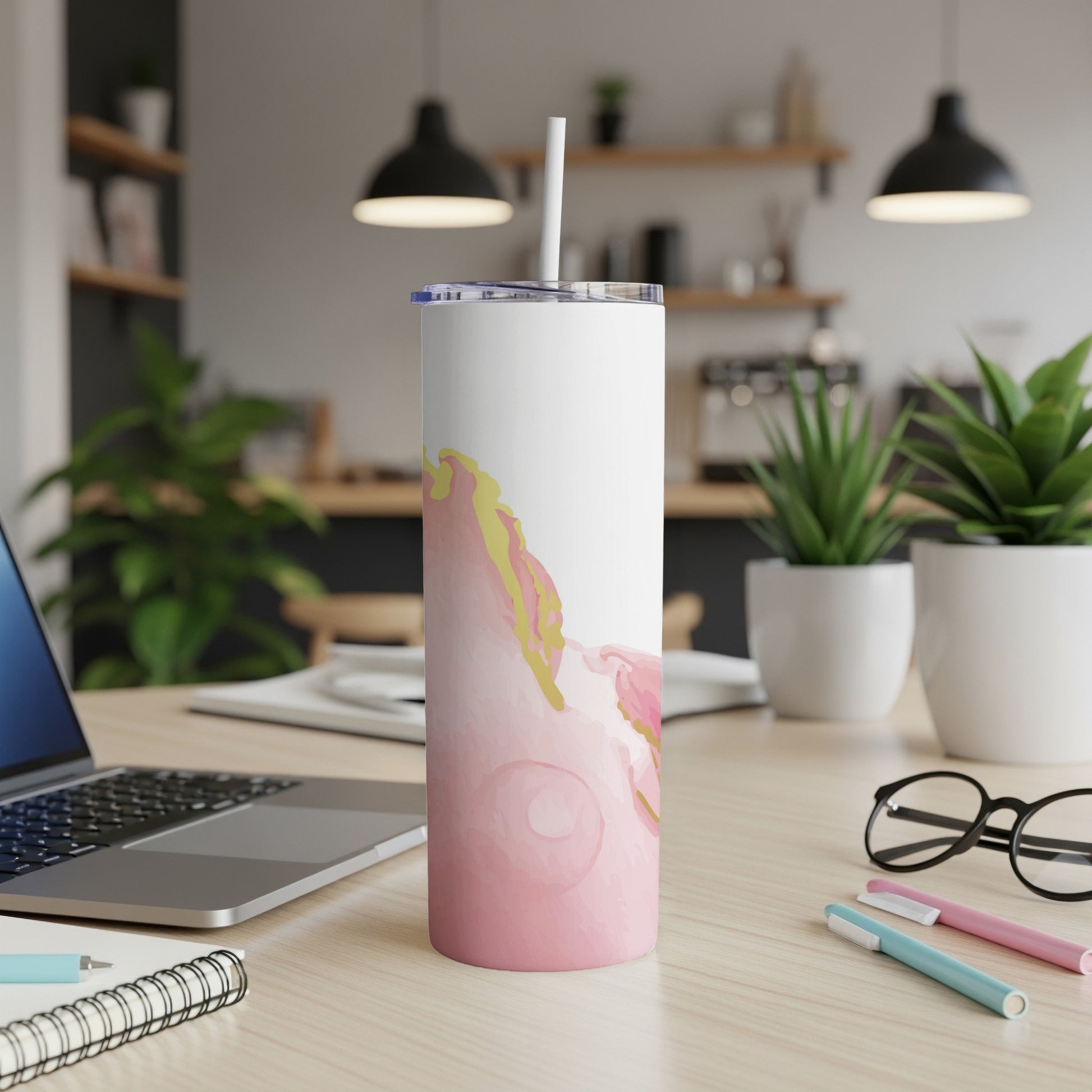 White tumbler with pink and gold abstract watercolor design on desk.