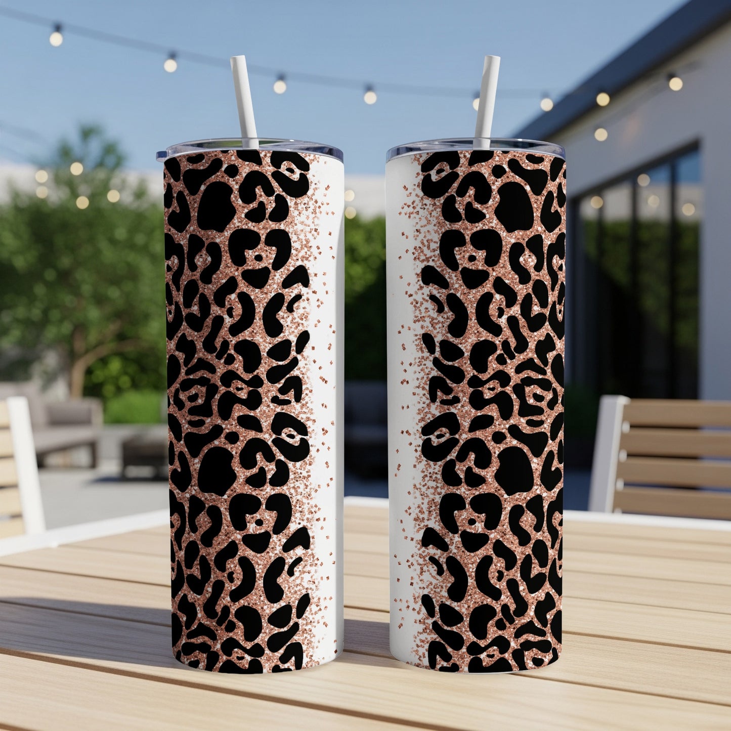 Two leopard print tumblers with rose gold glitter detail on a table.