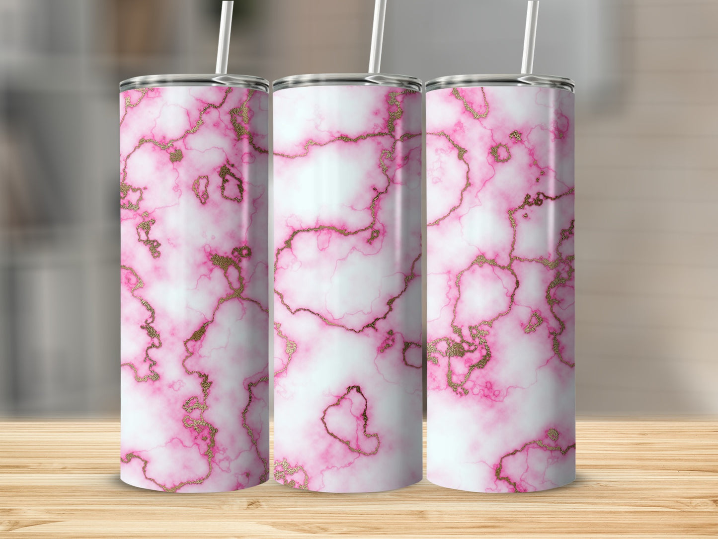 Three pink marble tumblers with gold veining on a wooden surface.
