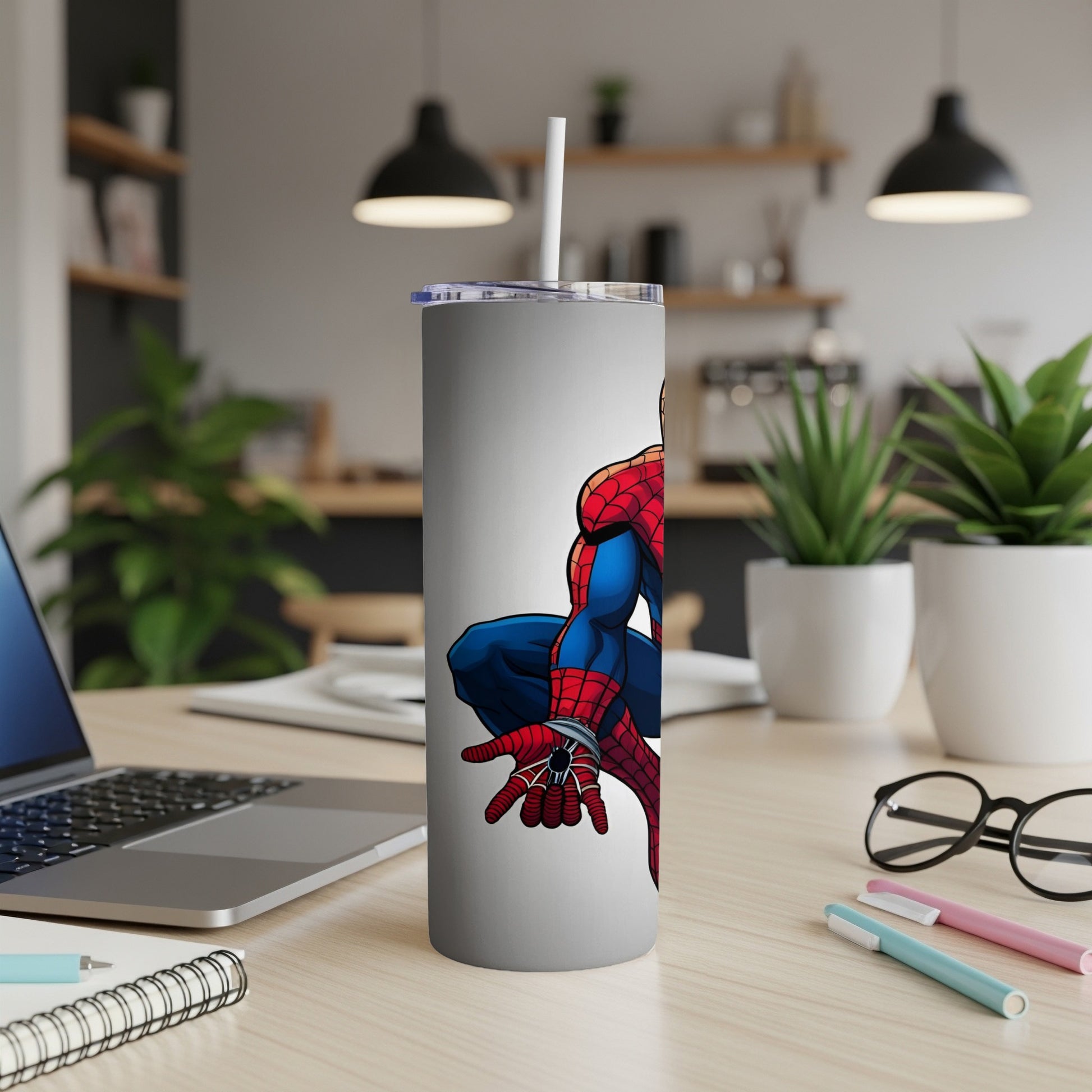 Spider-Man crouches on a white tumbler with a straw, desk background.