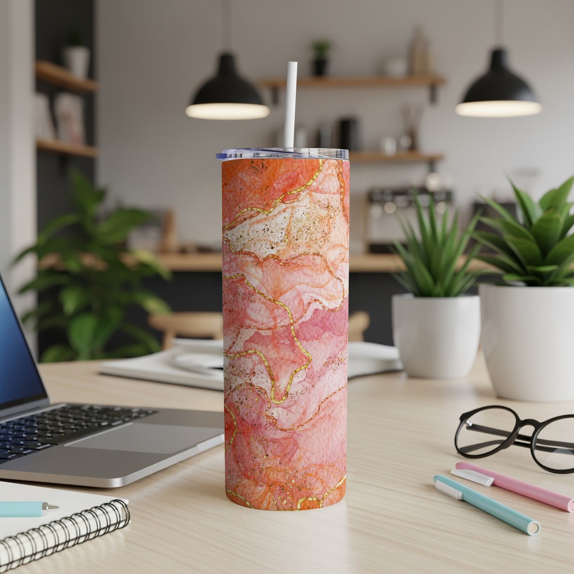 Orange and pink marble pattern tumbler with gold accents on a desk.