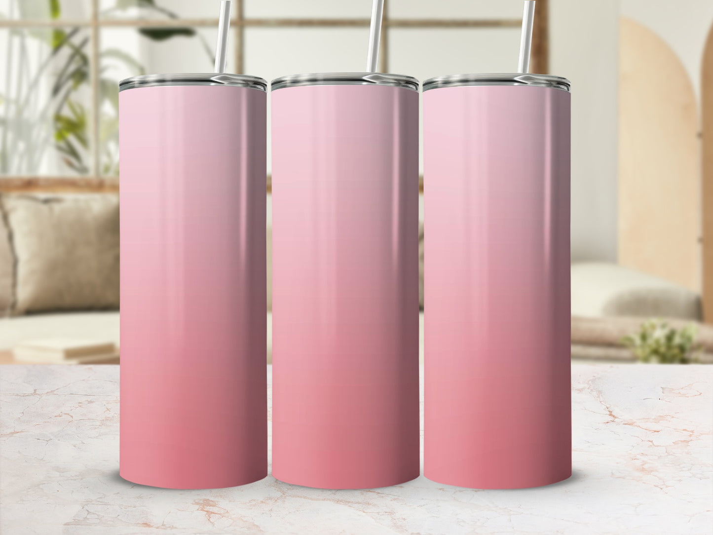 Three pink gradient tumblers with straws on a marble countertop.