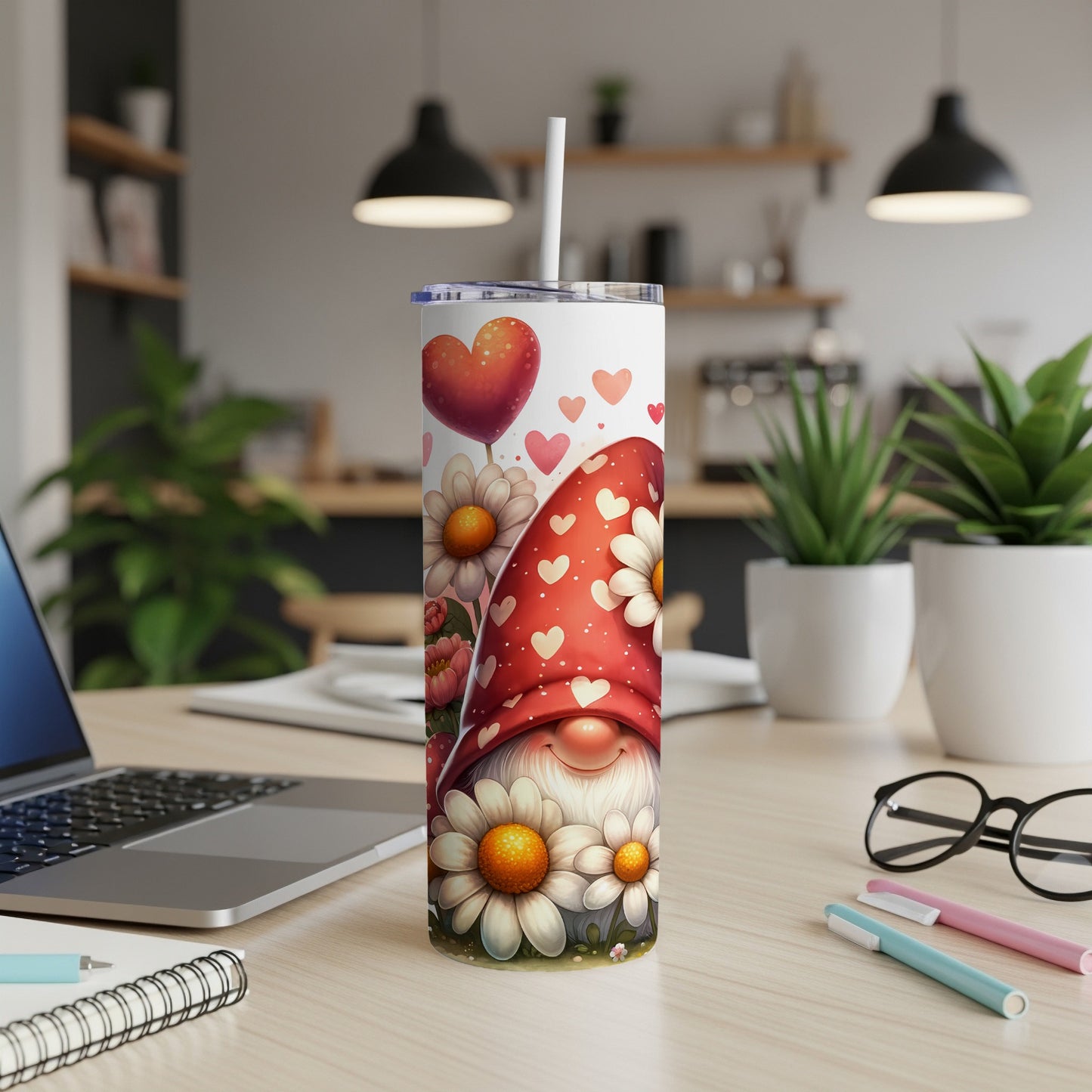 Gnome with hearts and flowers on a white tumbler with straw, on a desk.