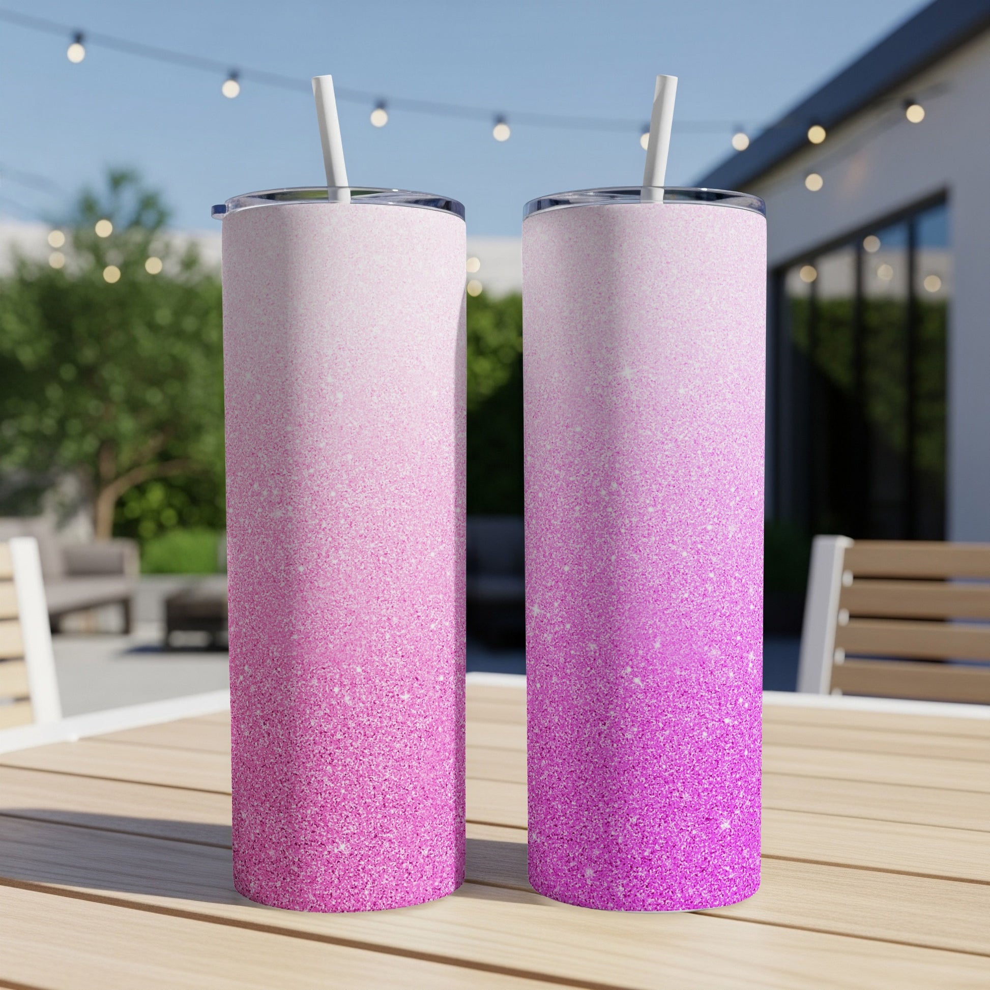 Two pink glitter ombre tumblers with straws on a wooden table.