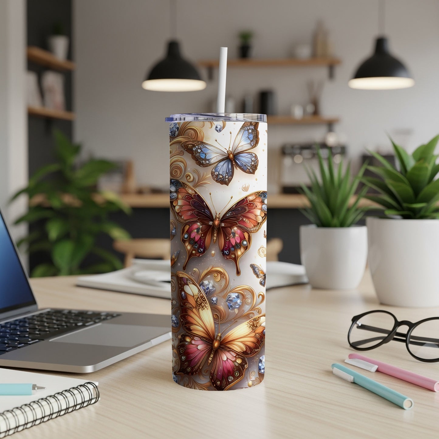Tumbler with ornate butterflies and floral details on a desk.