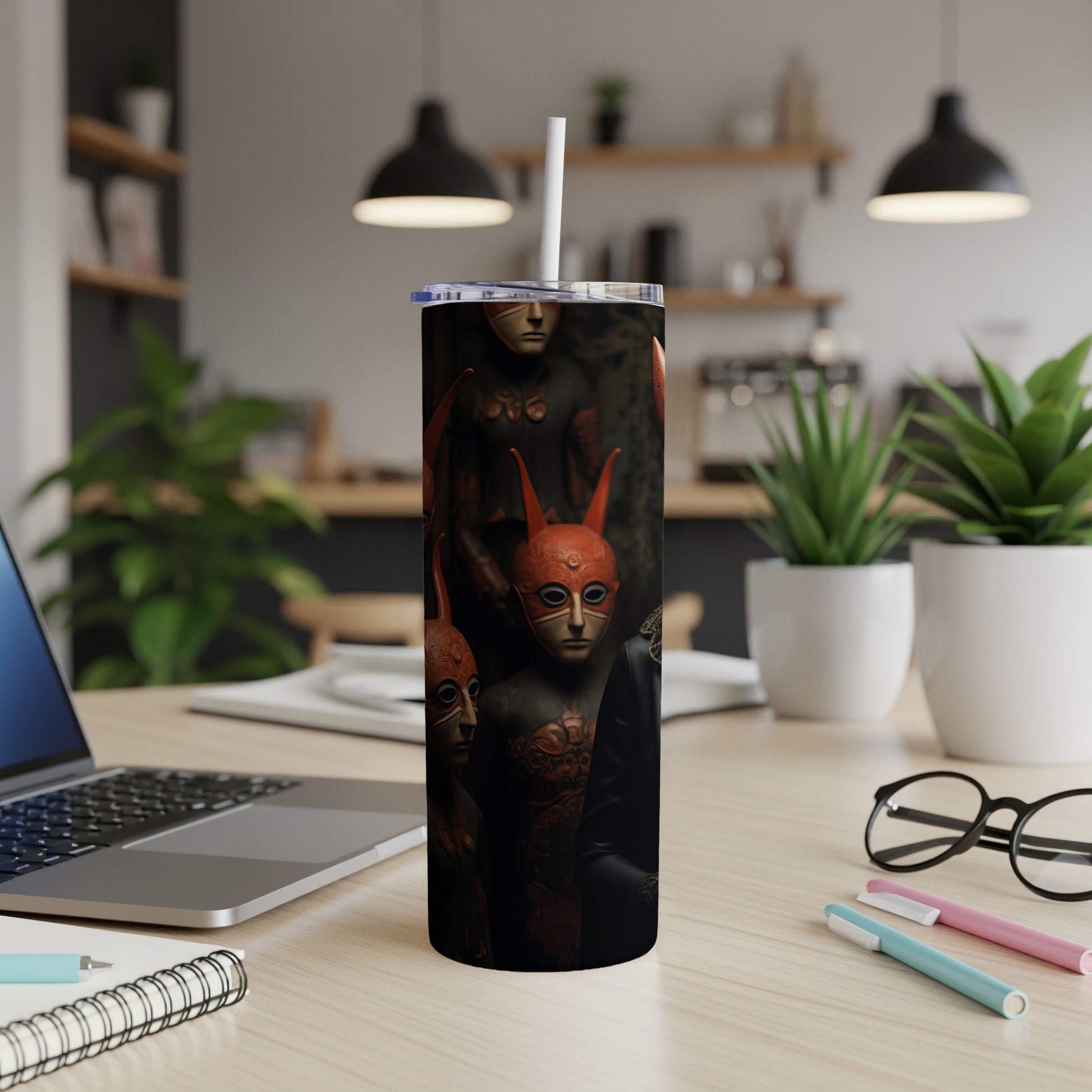 Tumbler with a dark print featuring masked figures with horns.