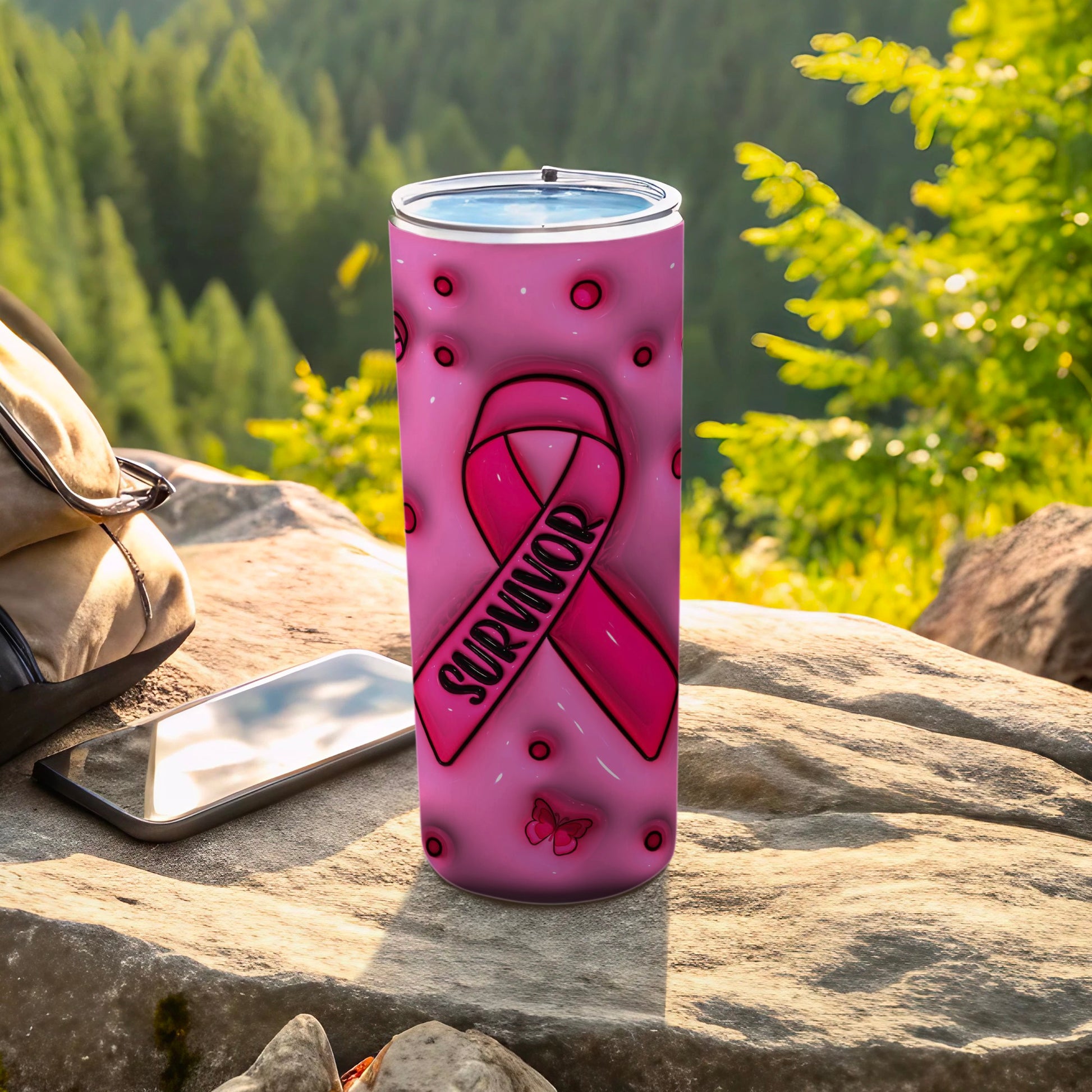 Pink tumbler with "Survivor" ribbon and butterflies, outdoors.