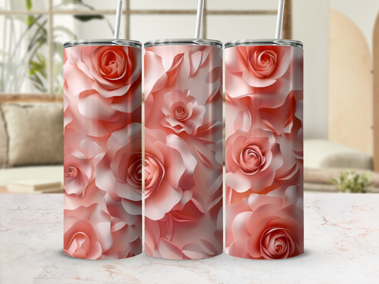 Three rose-patterned tumblers with straws arranged on a marbled surface.