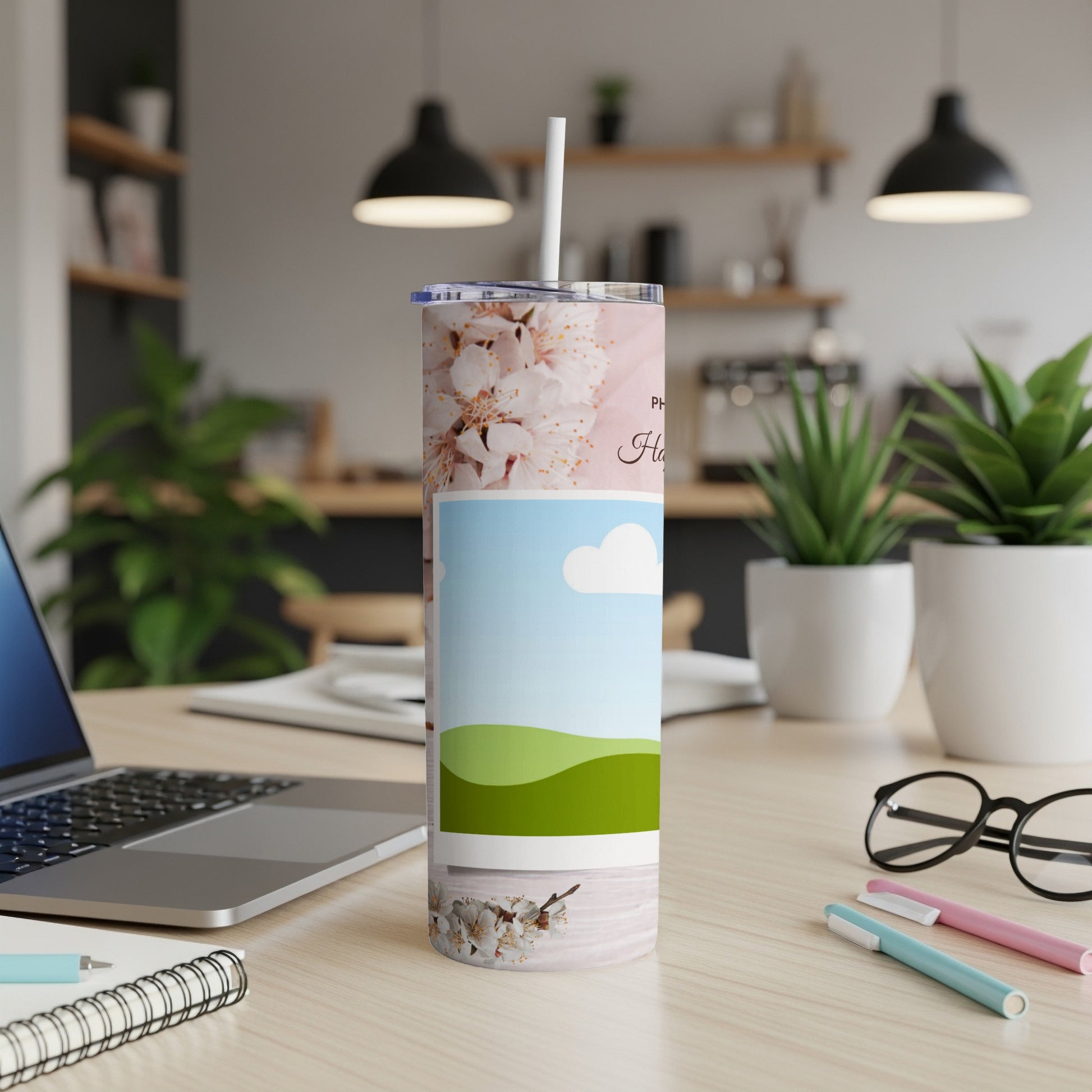 Tumbler with cherry blossoms and landscape art, with a straw.