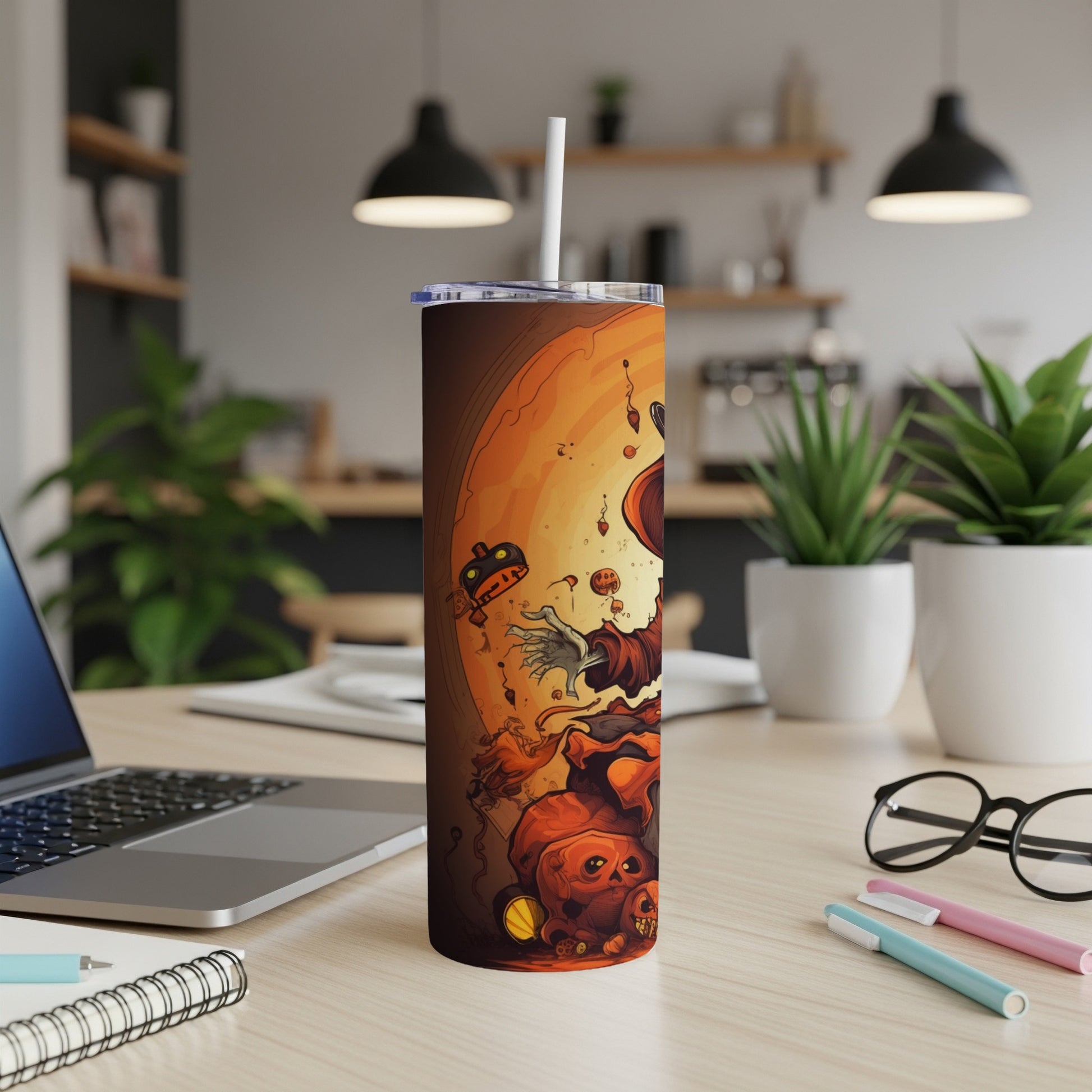 Halloween tumbler with spooky illustrations, straw, and lid on a desk.