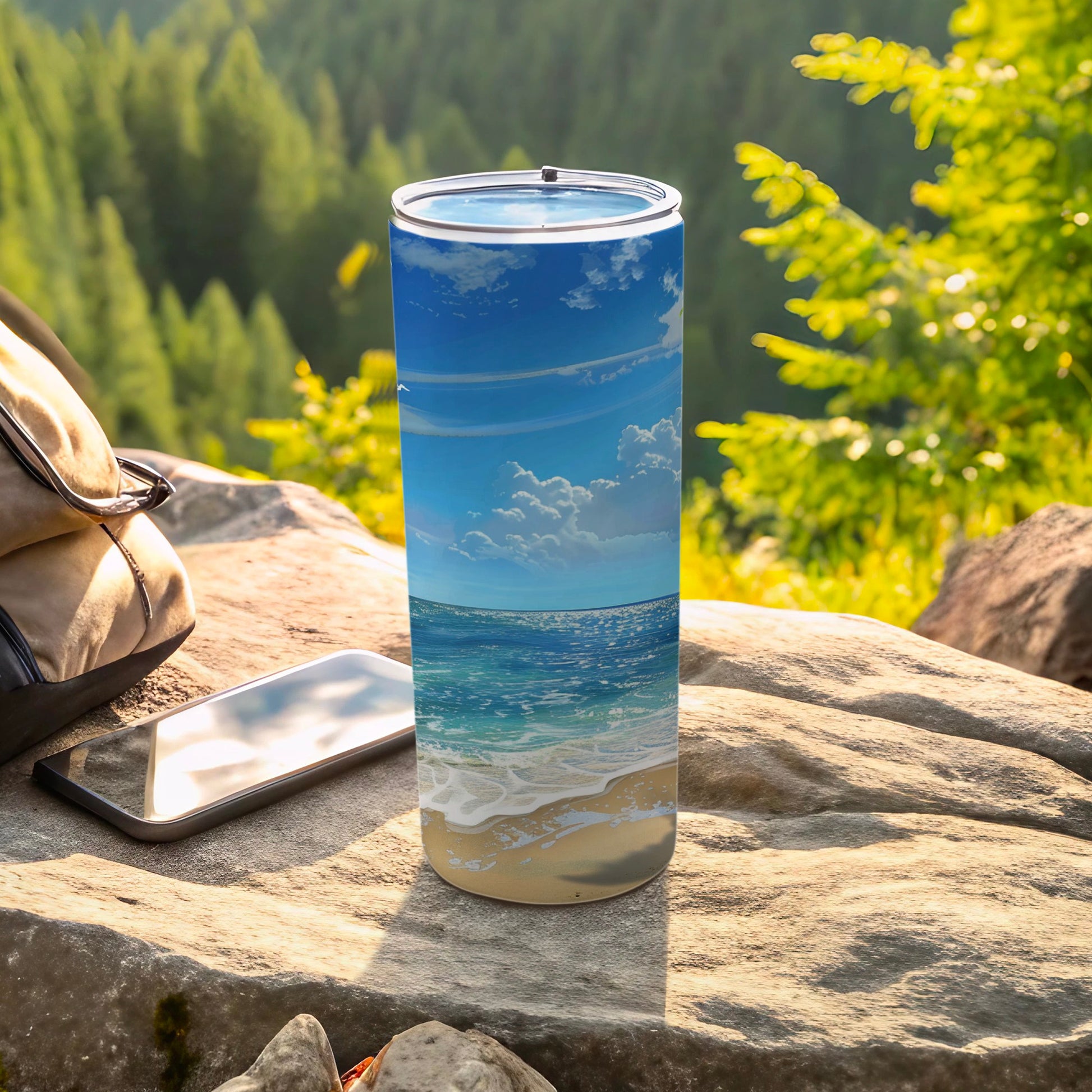 Beach scene tumbler on rock with backpack and phone.