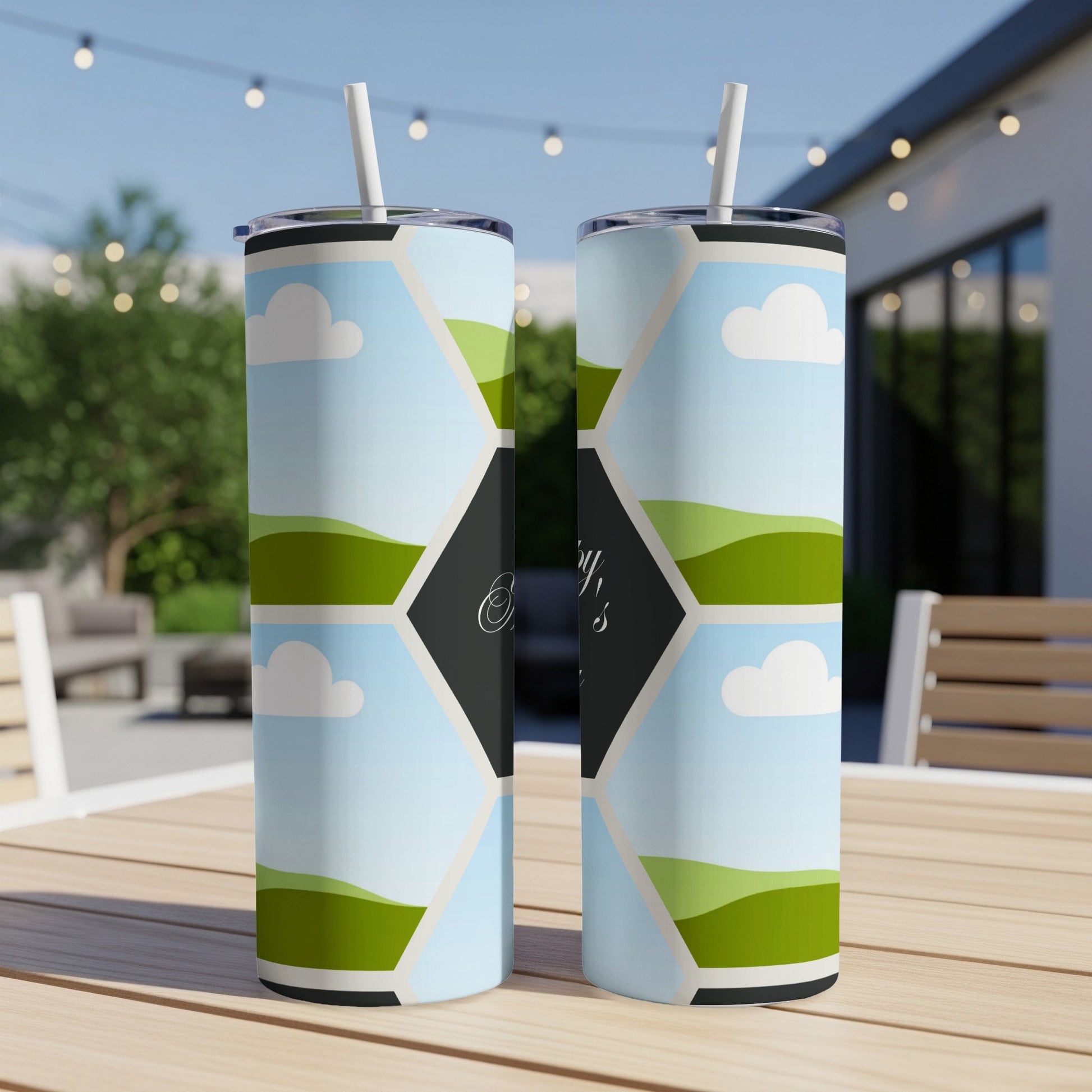 Two tumblers with hexagonal landscape pattern and white straws on a table.