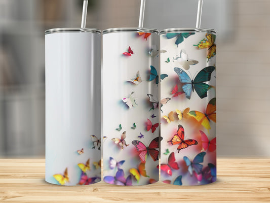 White and decorated tumblers with colorful butterflies on a wooden surface.