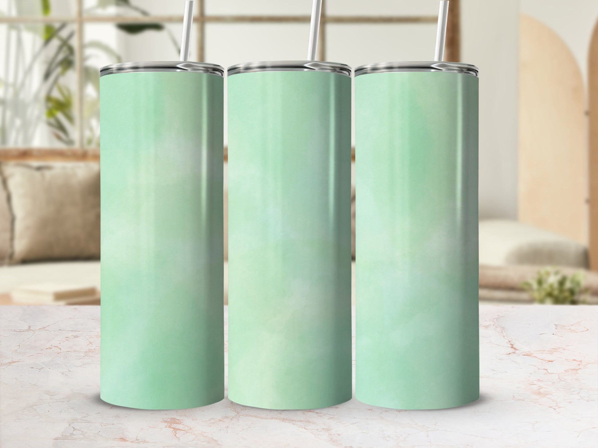 Three mint green tumblers with straws stand in a row on a marble surface.