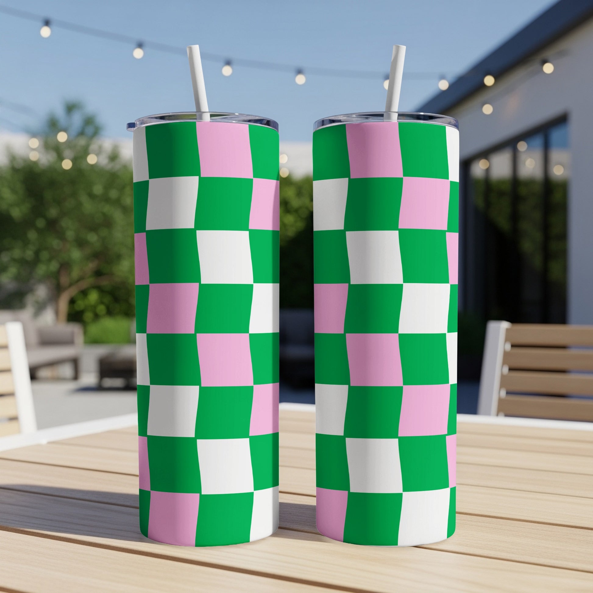 Two tall tumblers with a pink and green checkerboard pattern and white straws.