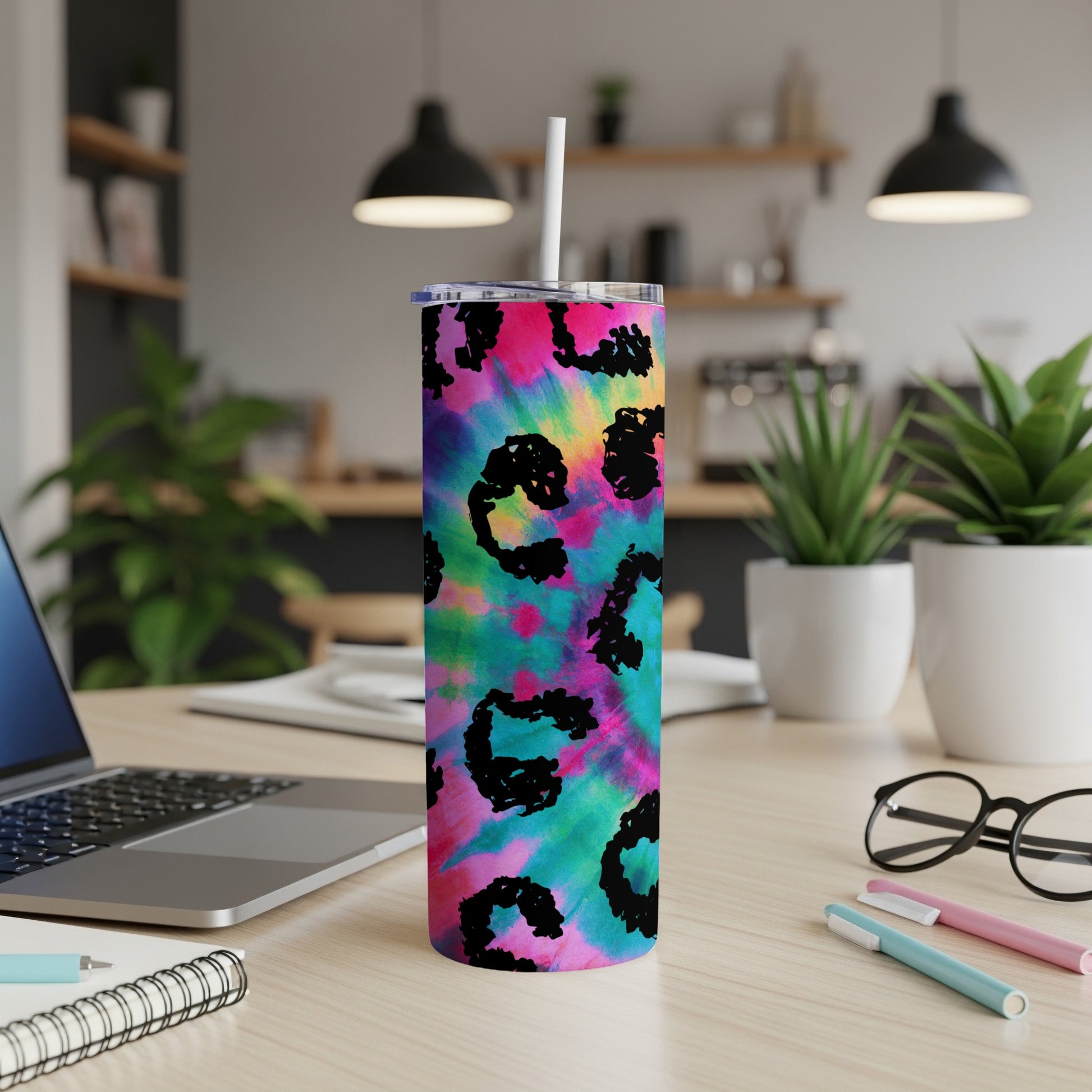 Tie-dye tumbler with black leopard print pattern on desk.