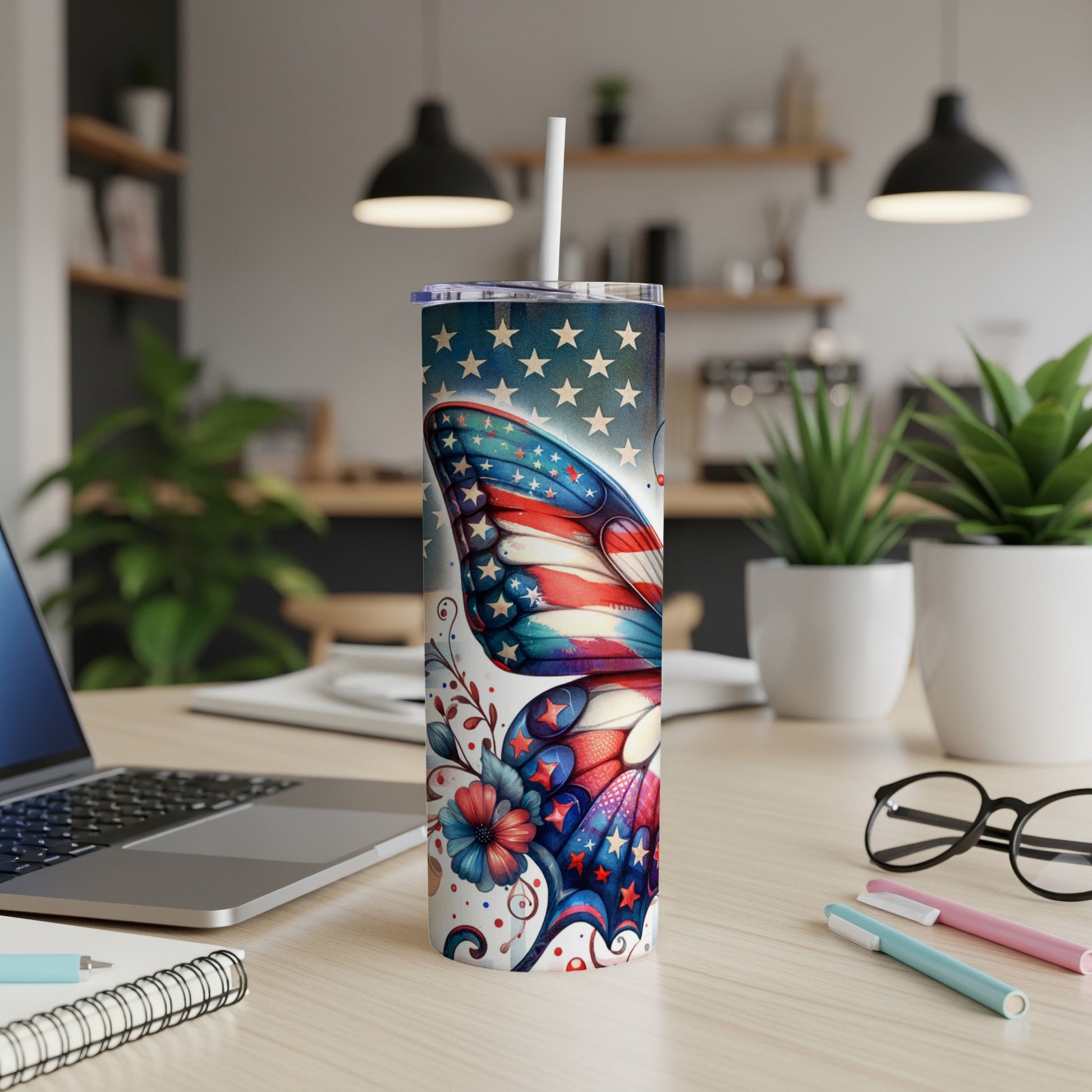 Tall tumbler with patriotic butterfly design, straw, and desk background.