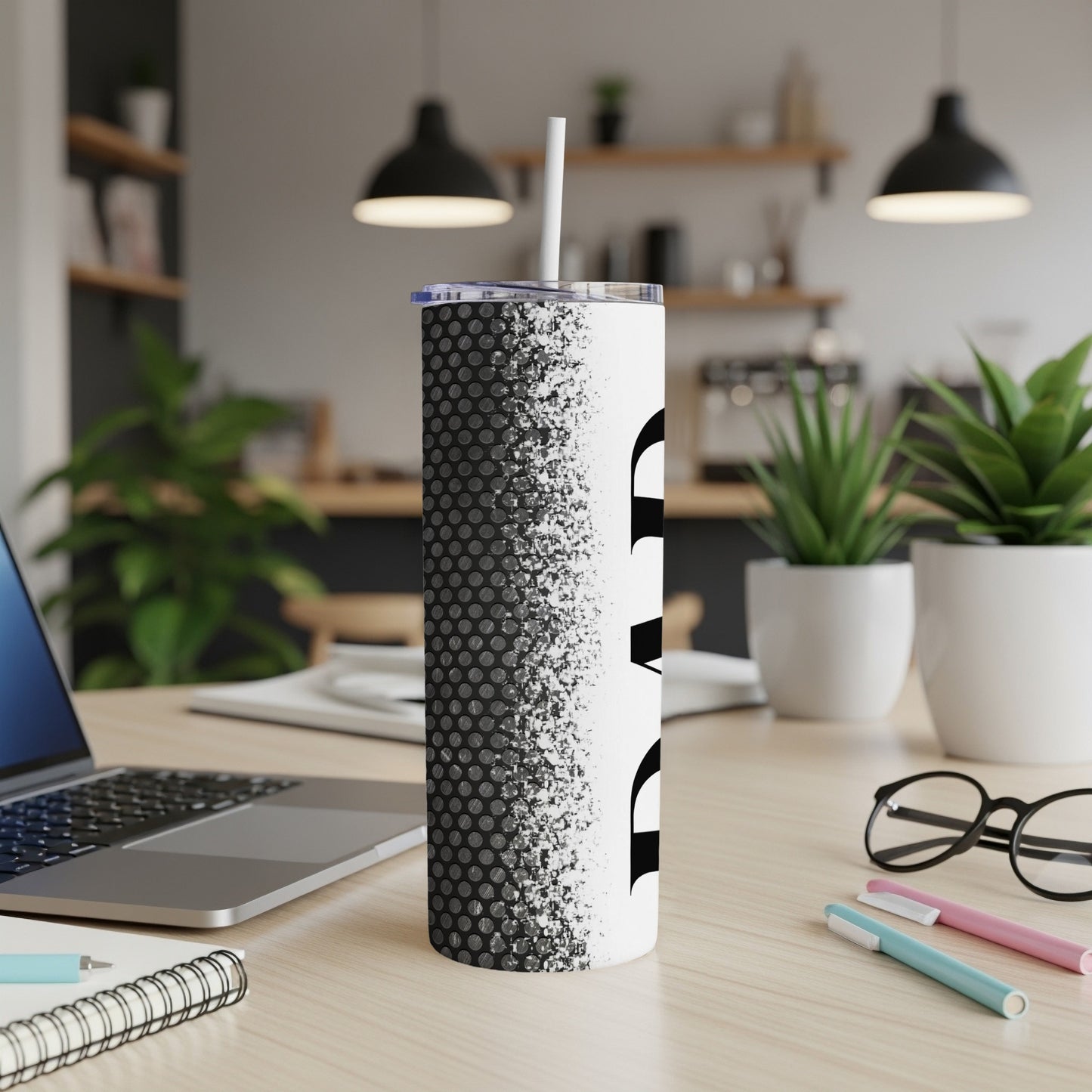 White tumbler with black dot pattern and abstract design, with straw.