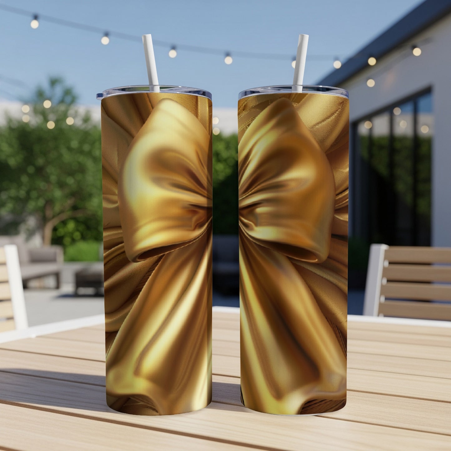 Two gold tumblers with a bow design on a wooden table outdoors.