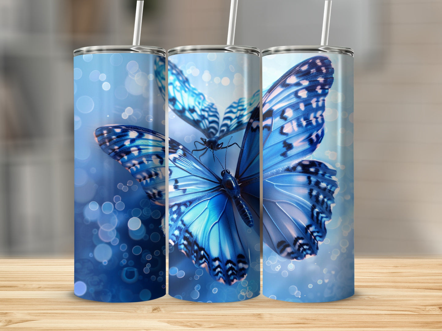 Three tumblers featuring blue butterflies with bokeh background effects.