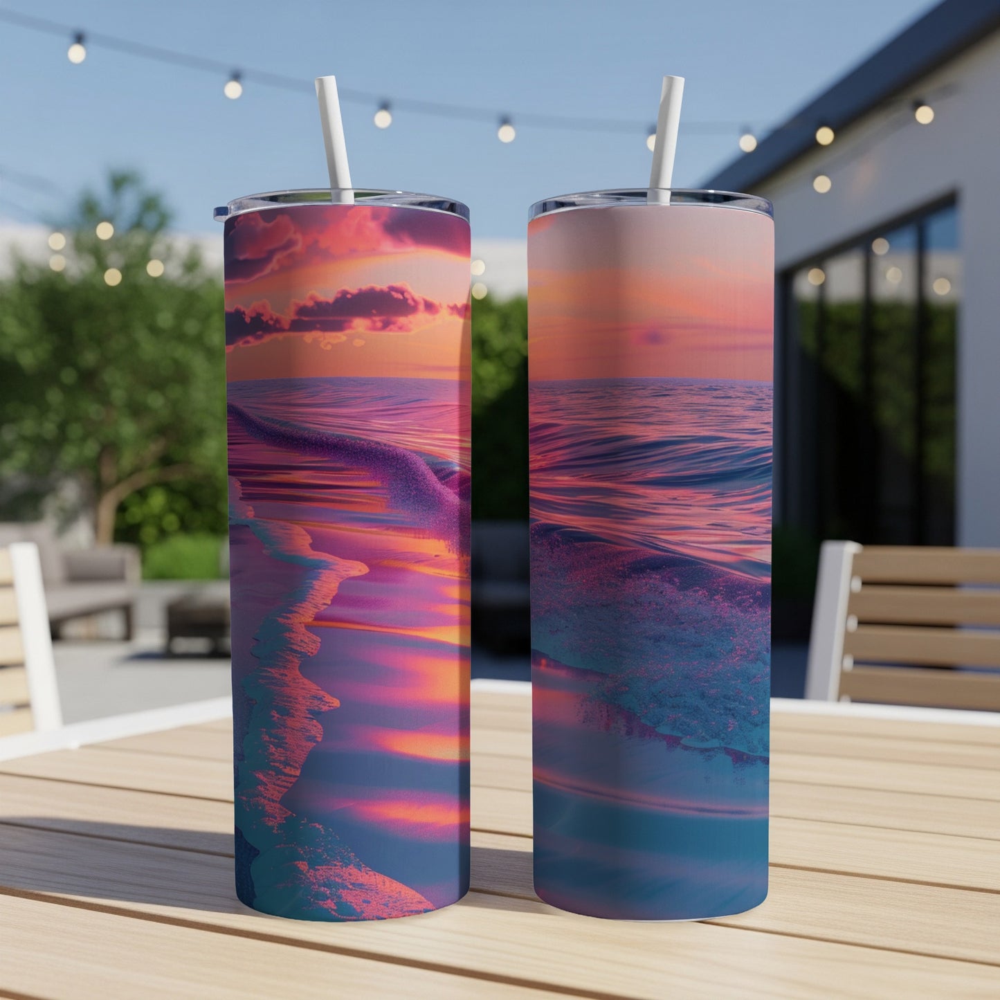Two tumblers with a sunset ocean wave graphic on a table outdoors.