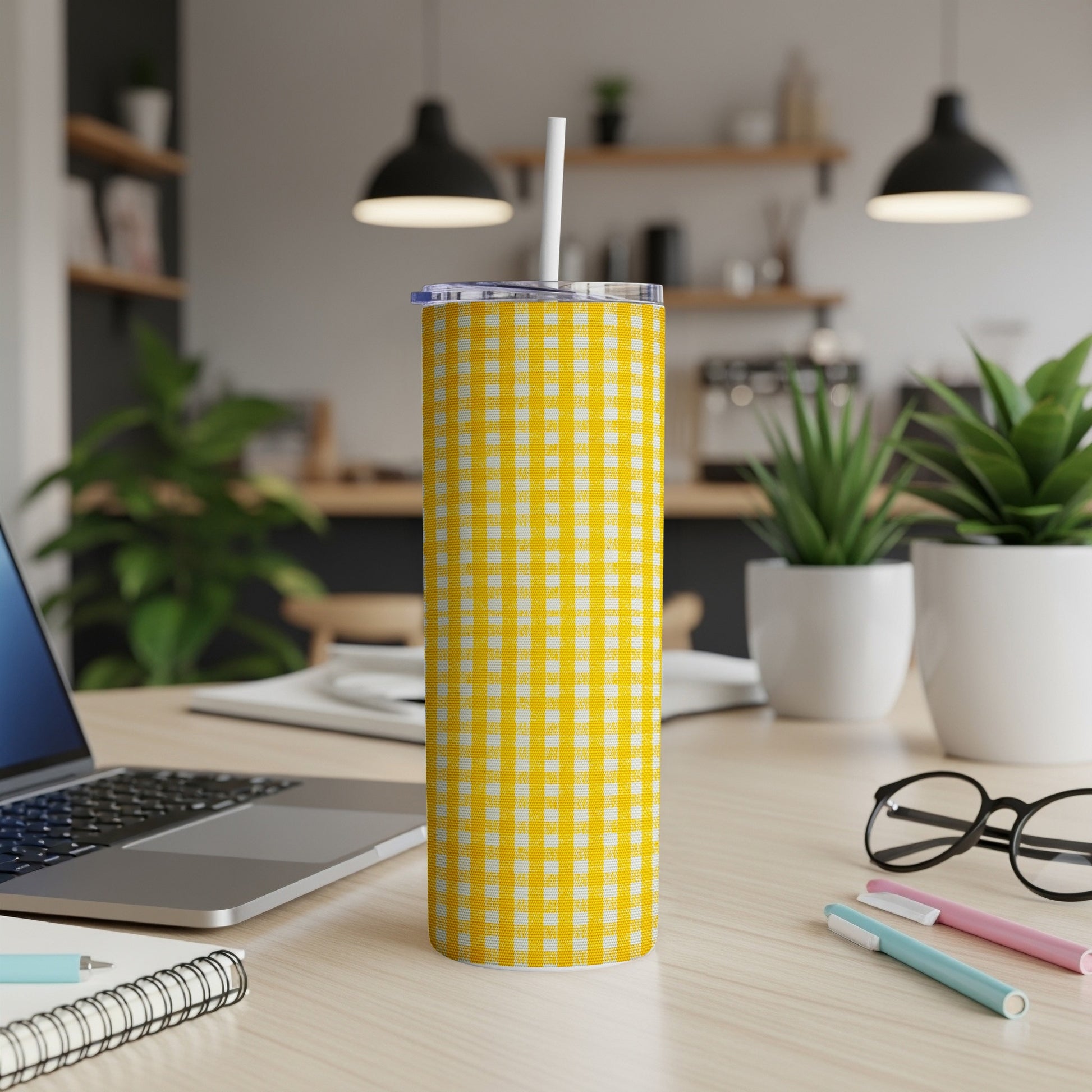 Yellow gingham tumbler with straw on a desk.