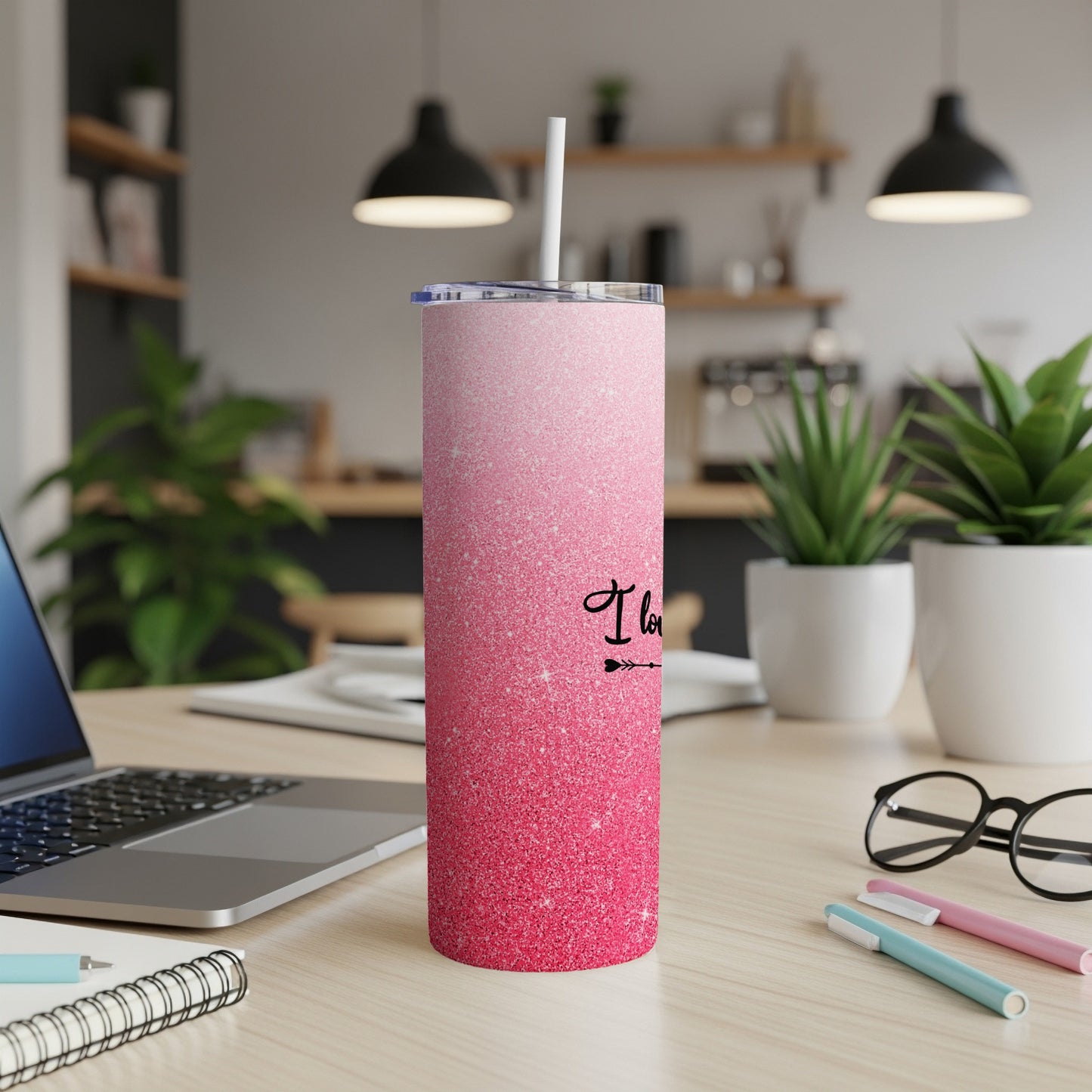 Pink glitter tumbler with "I love you" text on a wooden desk.
