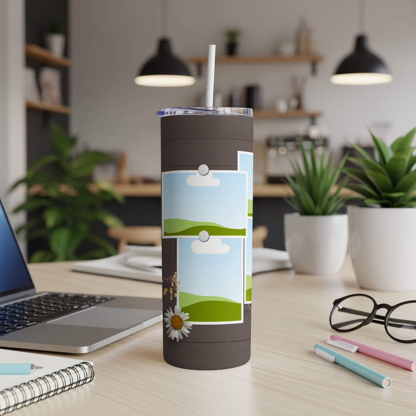 Dark tumbler with a straw and three framed landscape photos, including a daisy.