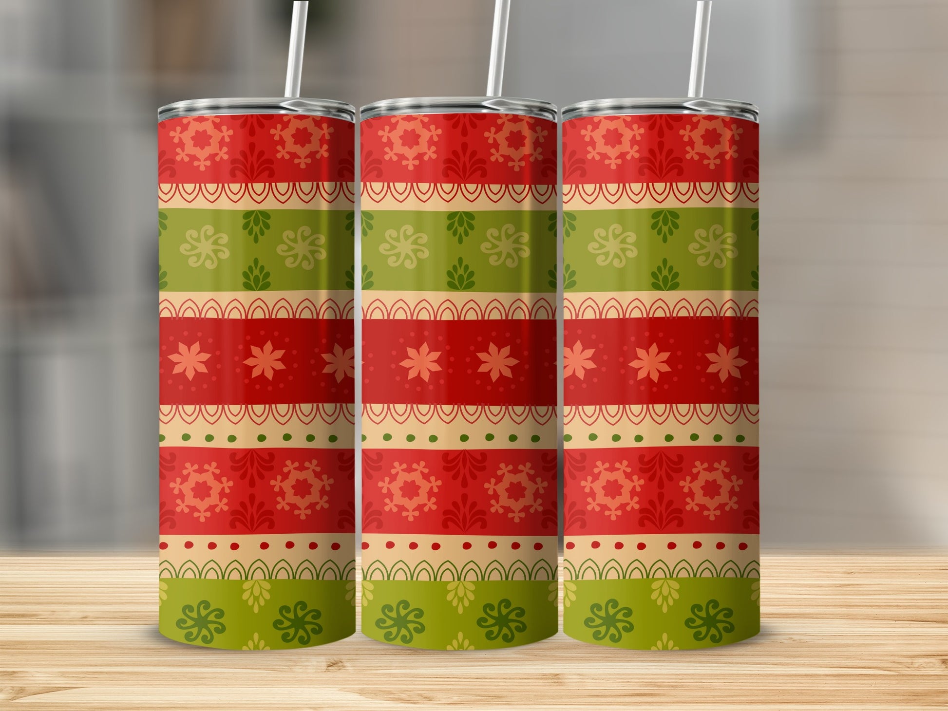 Three cylindrical tumblers with festive red, green, and gold striped patterns.