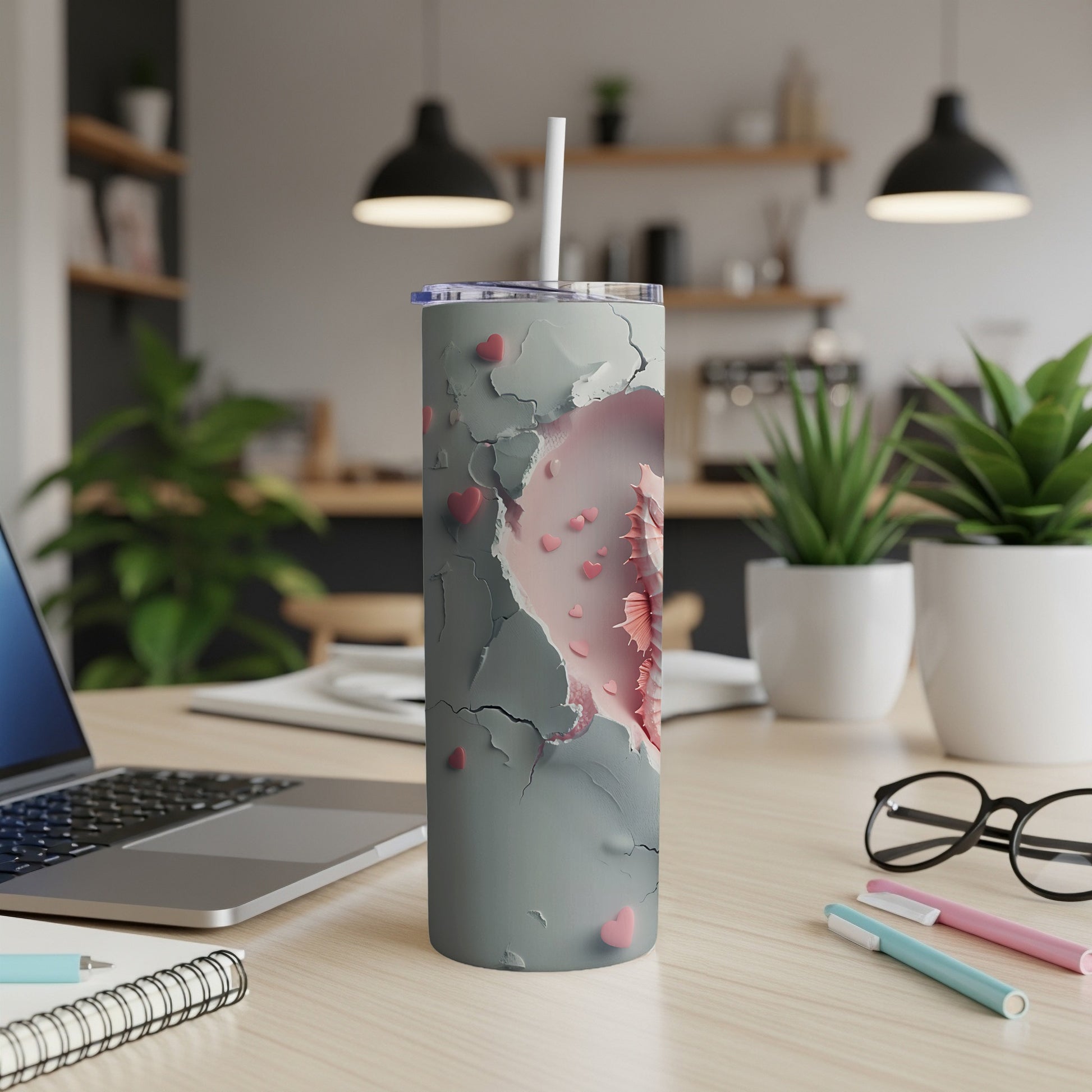 Gray tumbler with cracked paint revealing pink hearts, straw inserted.