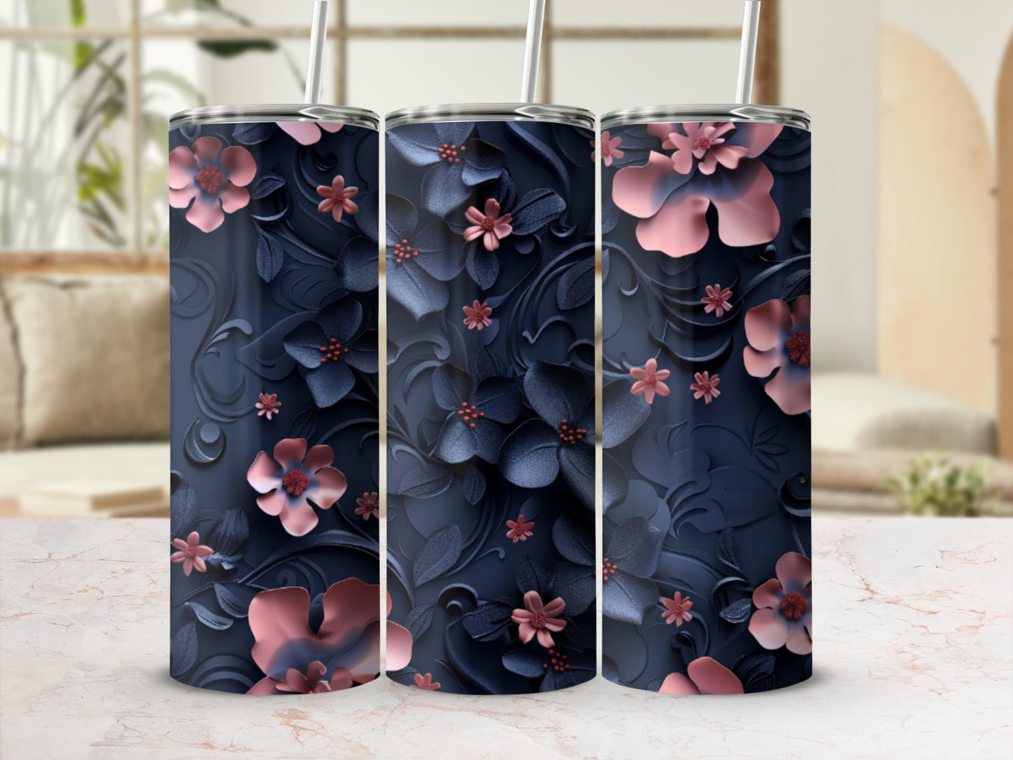 Three navy tumblers with pink floral embossing on a marbled surface.