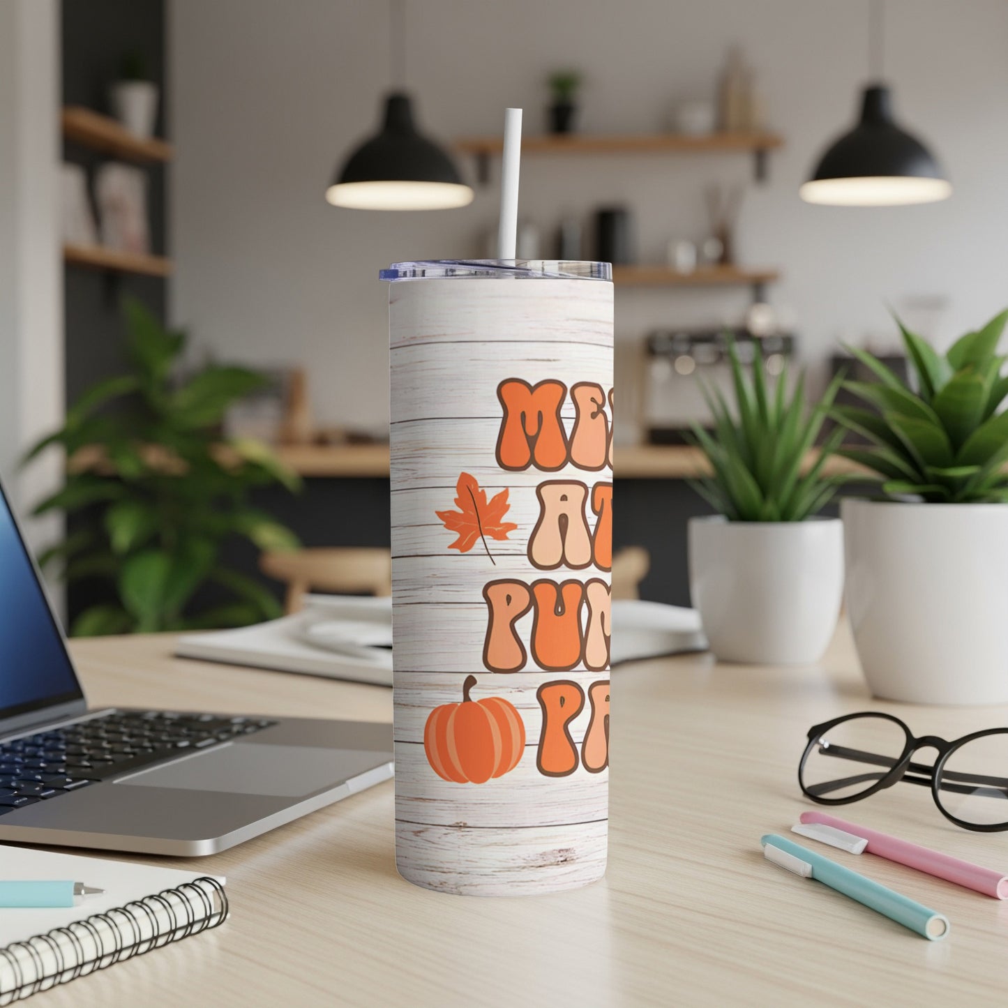 "Merry Pumpkin Spice" text on a wood-grain tumbler with straw on a desk.
