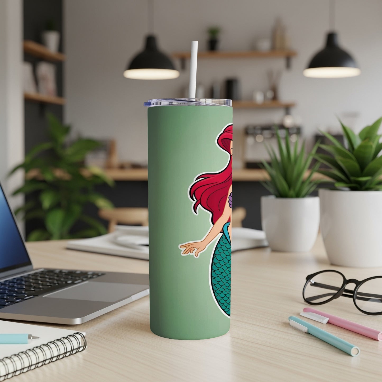 Ariel the mermaid on a sage green tumbler with straw, on a desk.