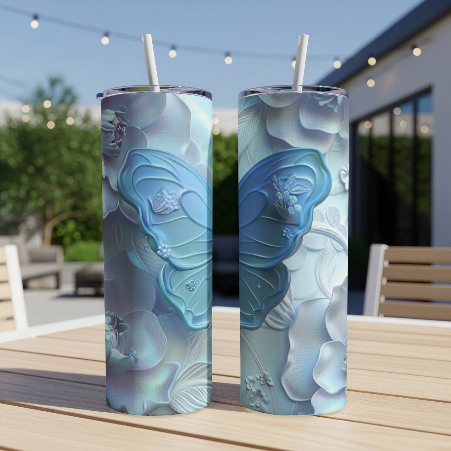 Two blue butterfly tumblers with floral patterns on a table outdoors.