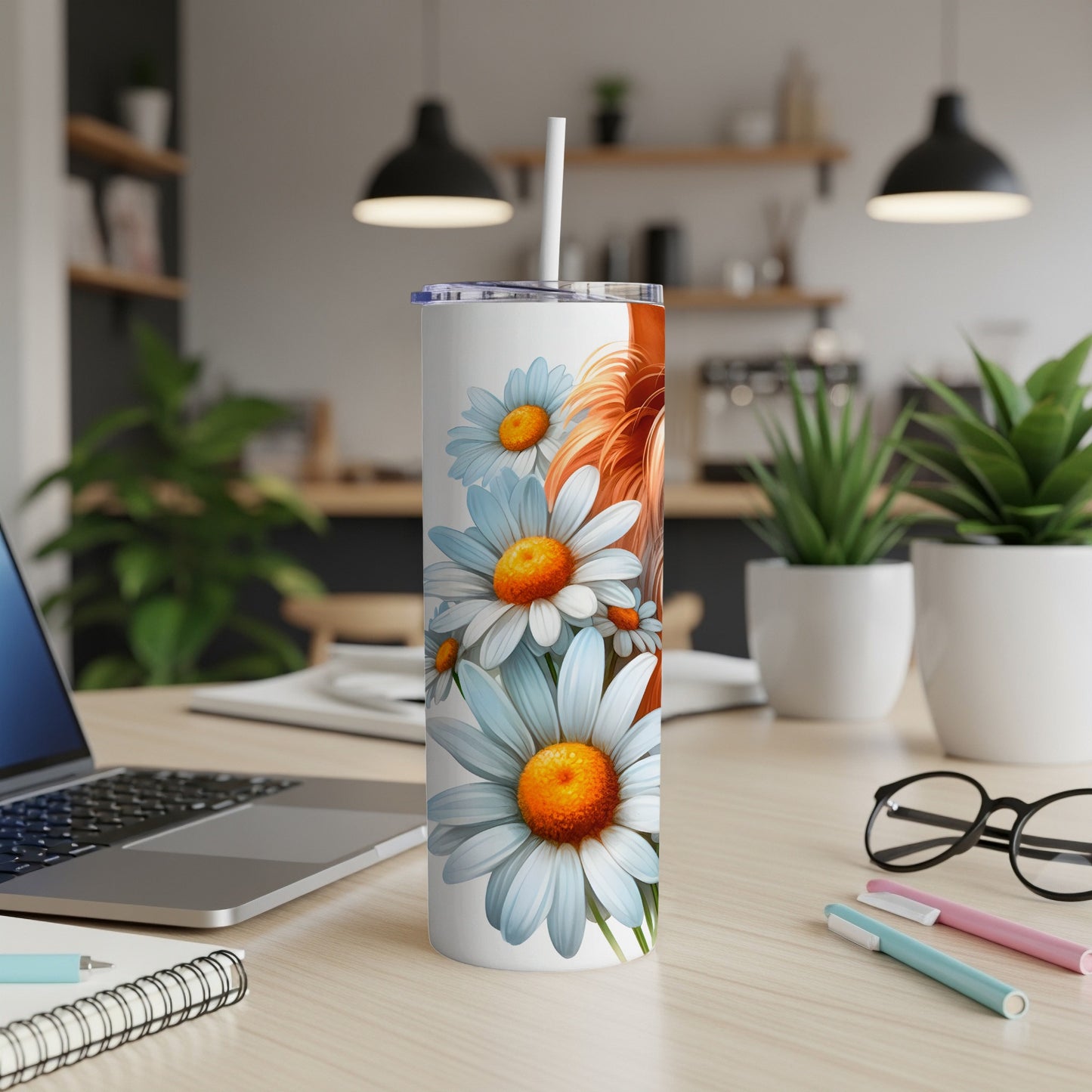 White tumbler with daisies and lion illustration on a desk.