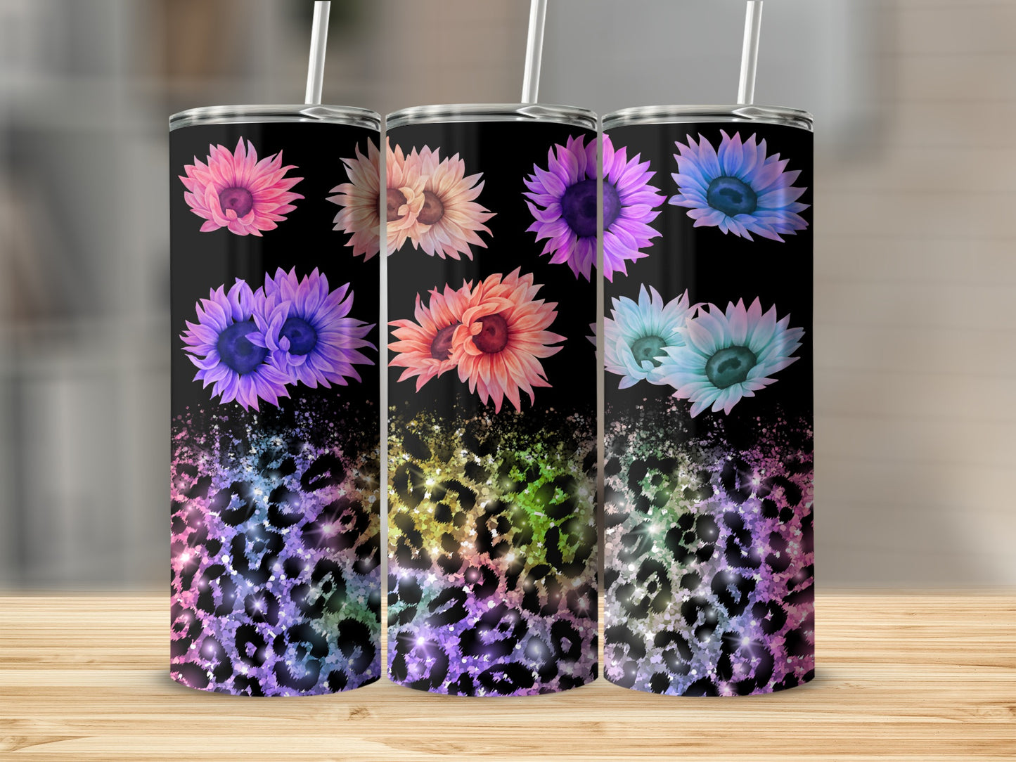 Three tall tumblers with floral and leopard print designs on a wooden surface.