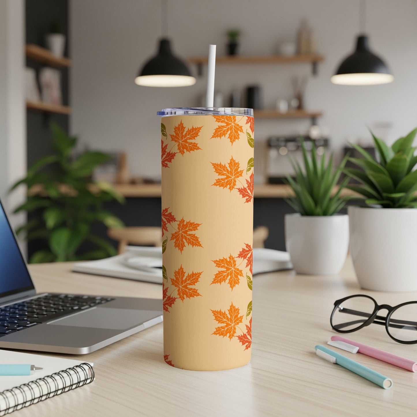 Beige tumbler with autumn leaf pattern and white straw.
