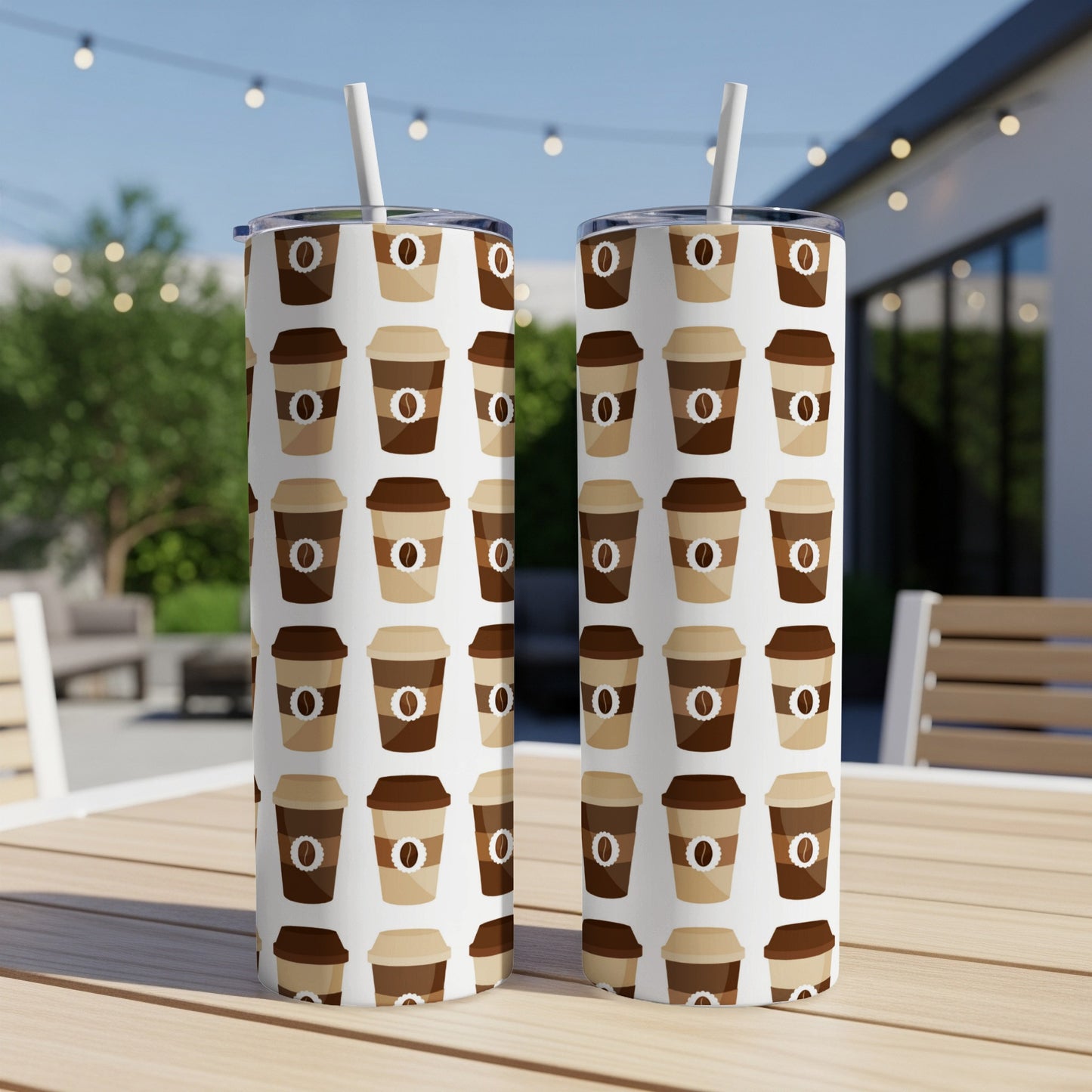 Two tall, patterned tumblers with coffee cup designs sit on an outdoor table.