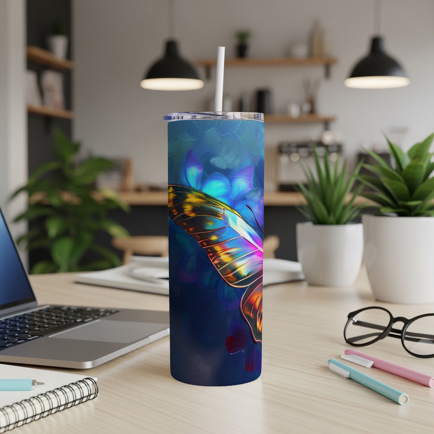 Blue tumbler with a glowing butterfly and floral design on a desk.