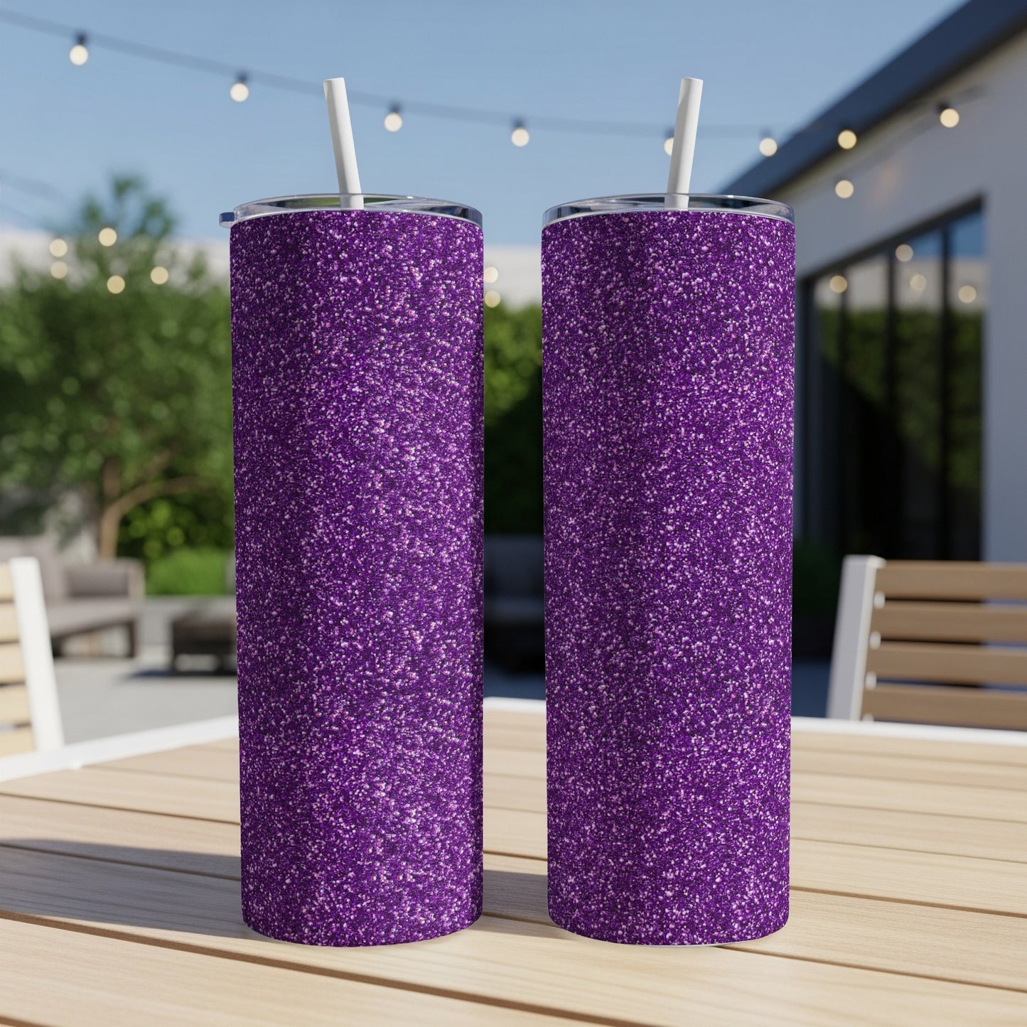 Two purple glitter tumblers with white straws on a wooden table.